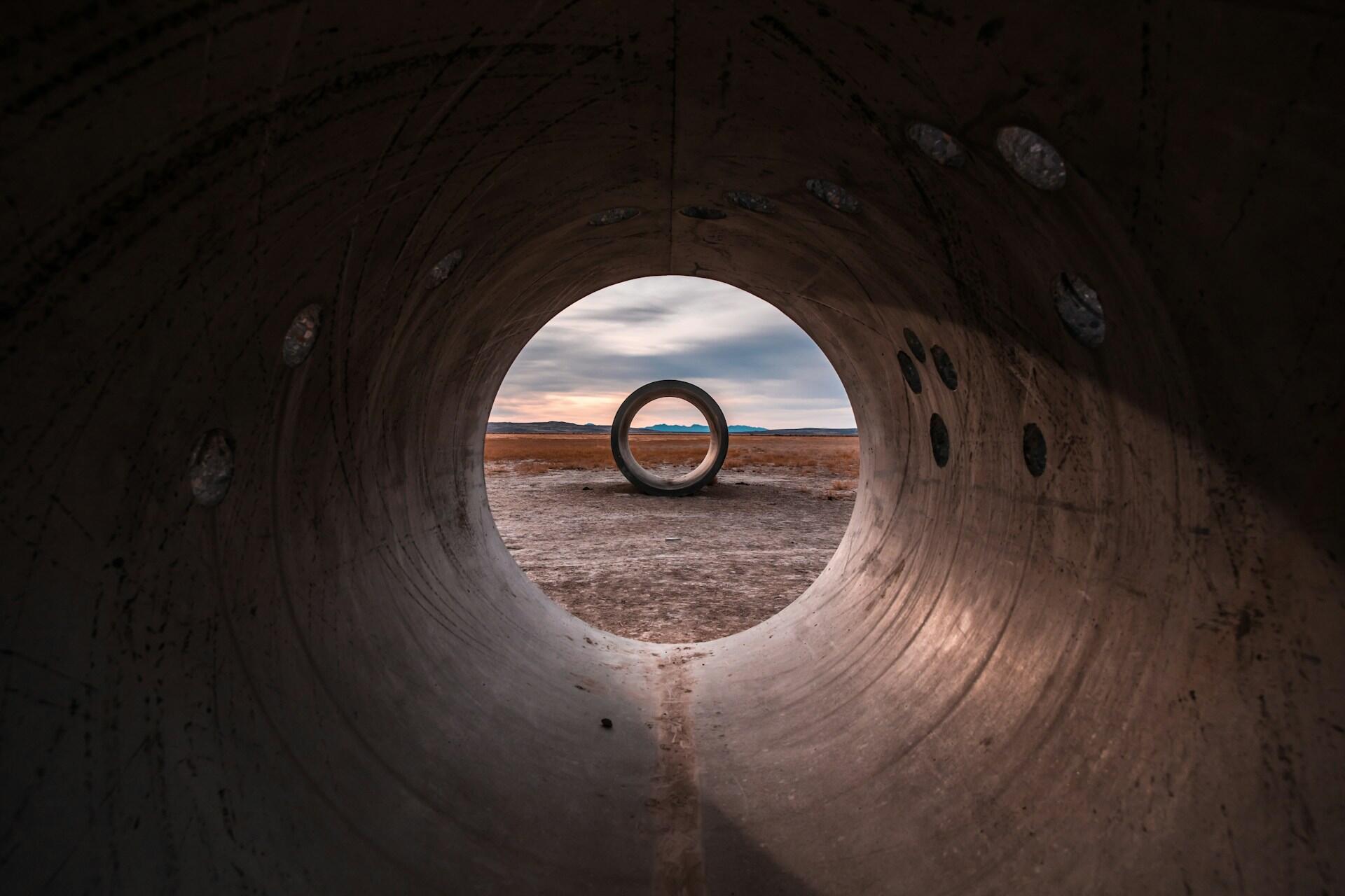 prise de vue d'un tunnel gris où l'on peut distinguer un deuxième tunnel qui prend la forme d'un cercle. 