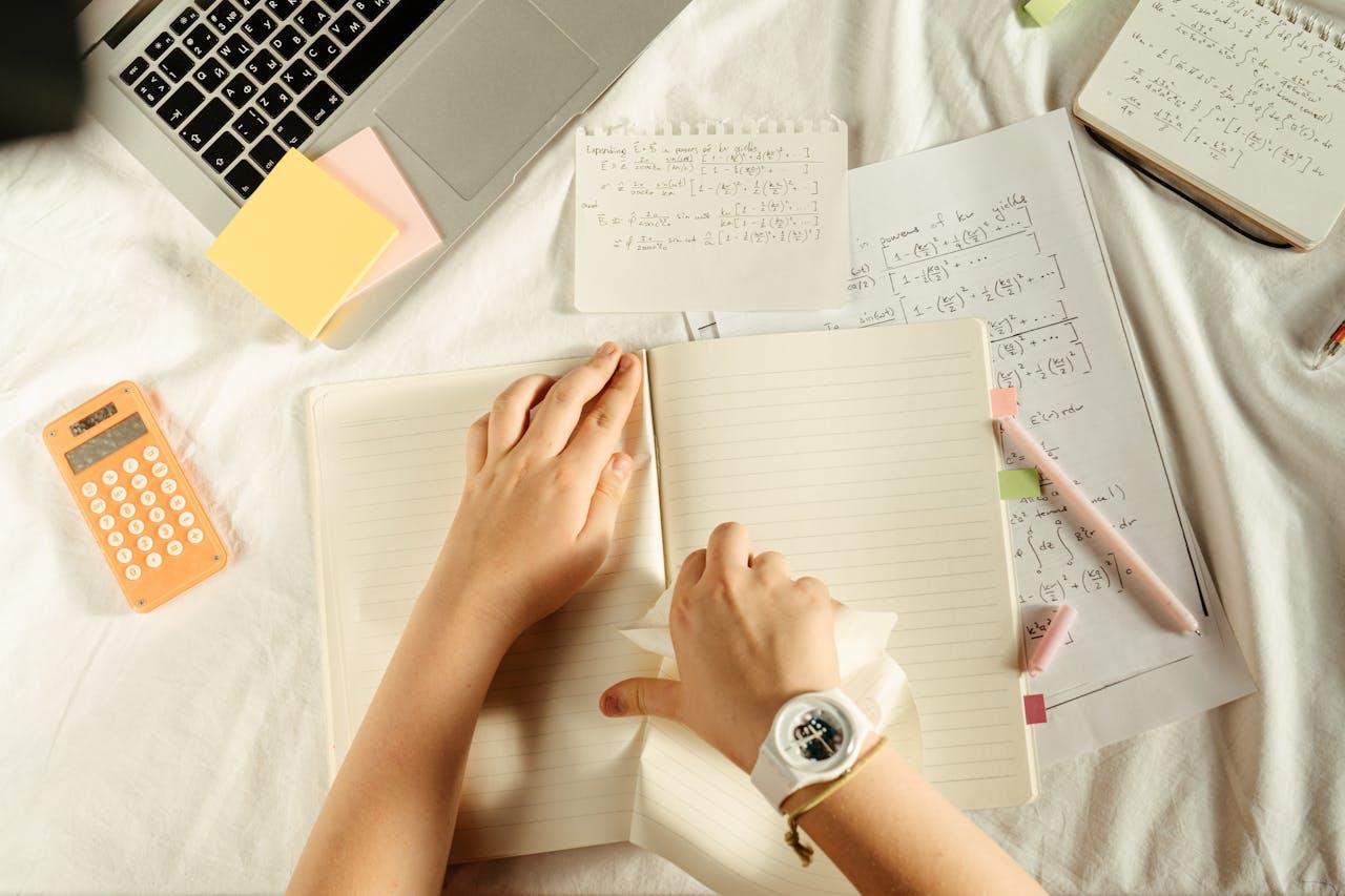Cahier ouvert avec quelqu'un dont on ne voit que les mains qui déchirent une page. 