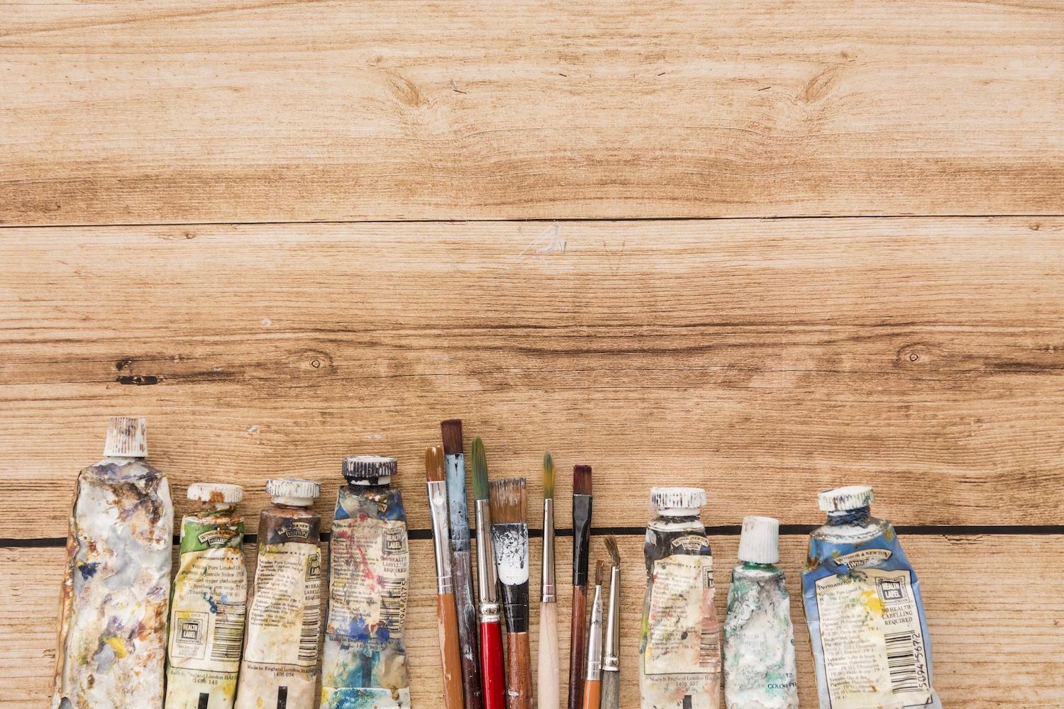 Pots de peinture et pinceaux sur un fond en bois.