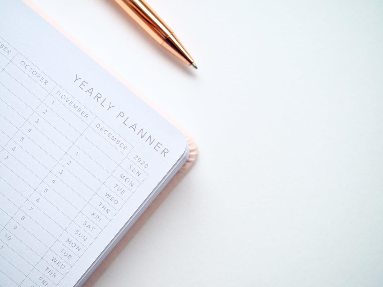 Agenda avec un stylo posés sur une table blanche