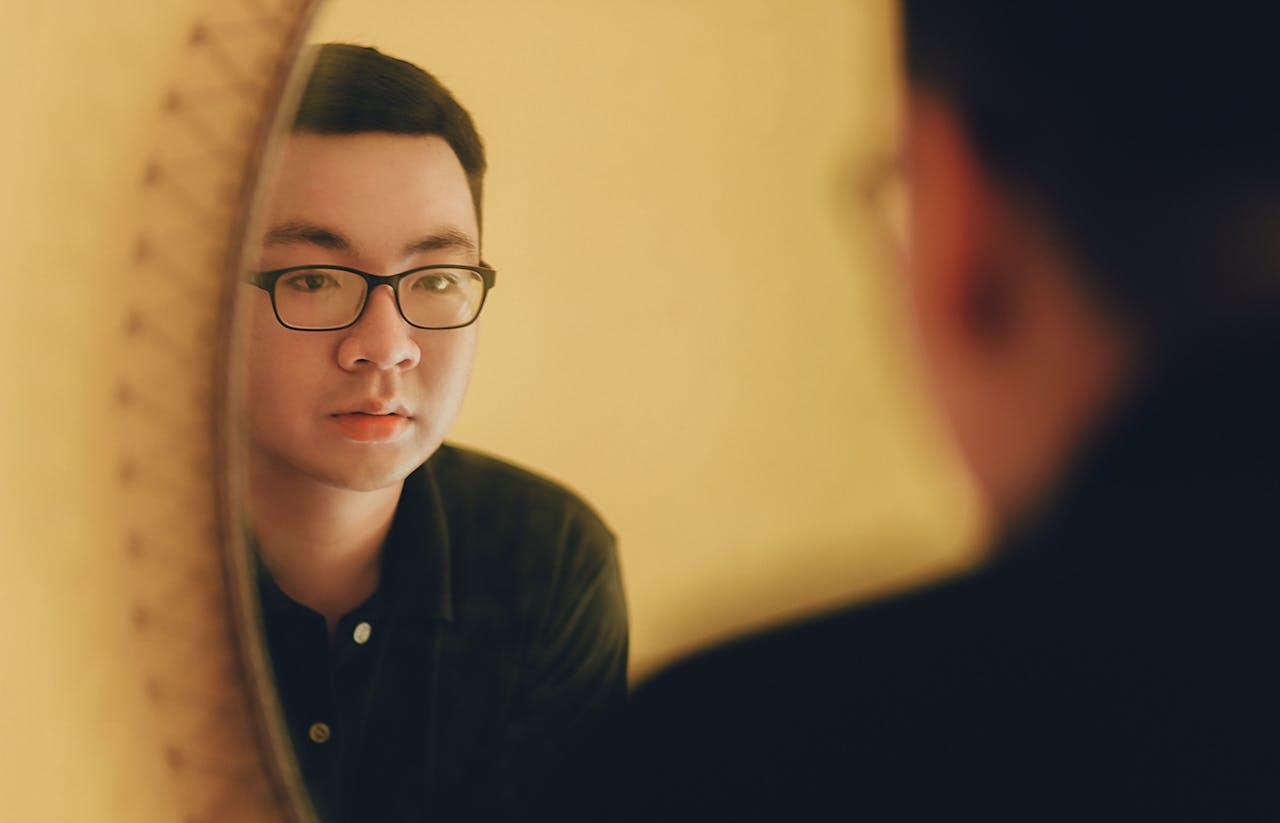Jeune homme asiatique qui se regarde dans un miroir.