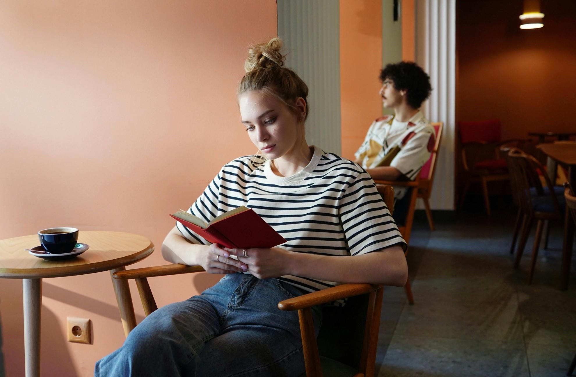 Une femme en train de lire un livre dans un café.