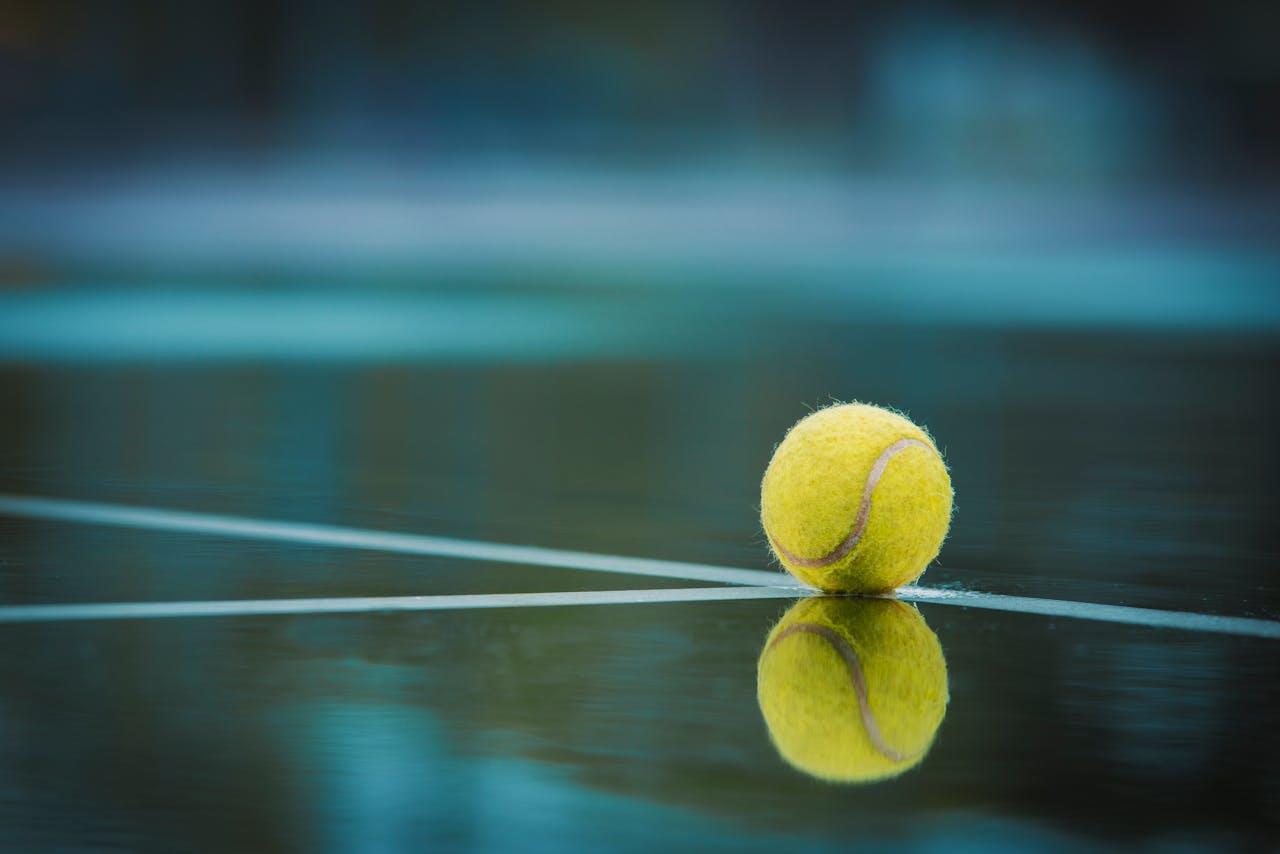 Balle de tennis posée sur un court en dur.