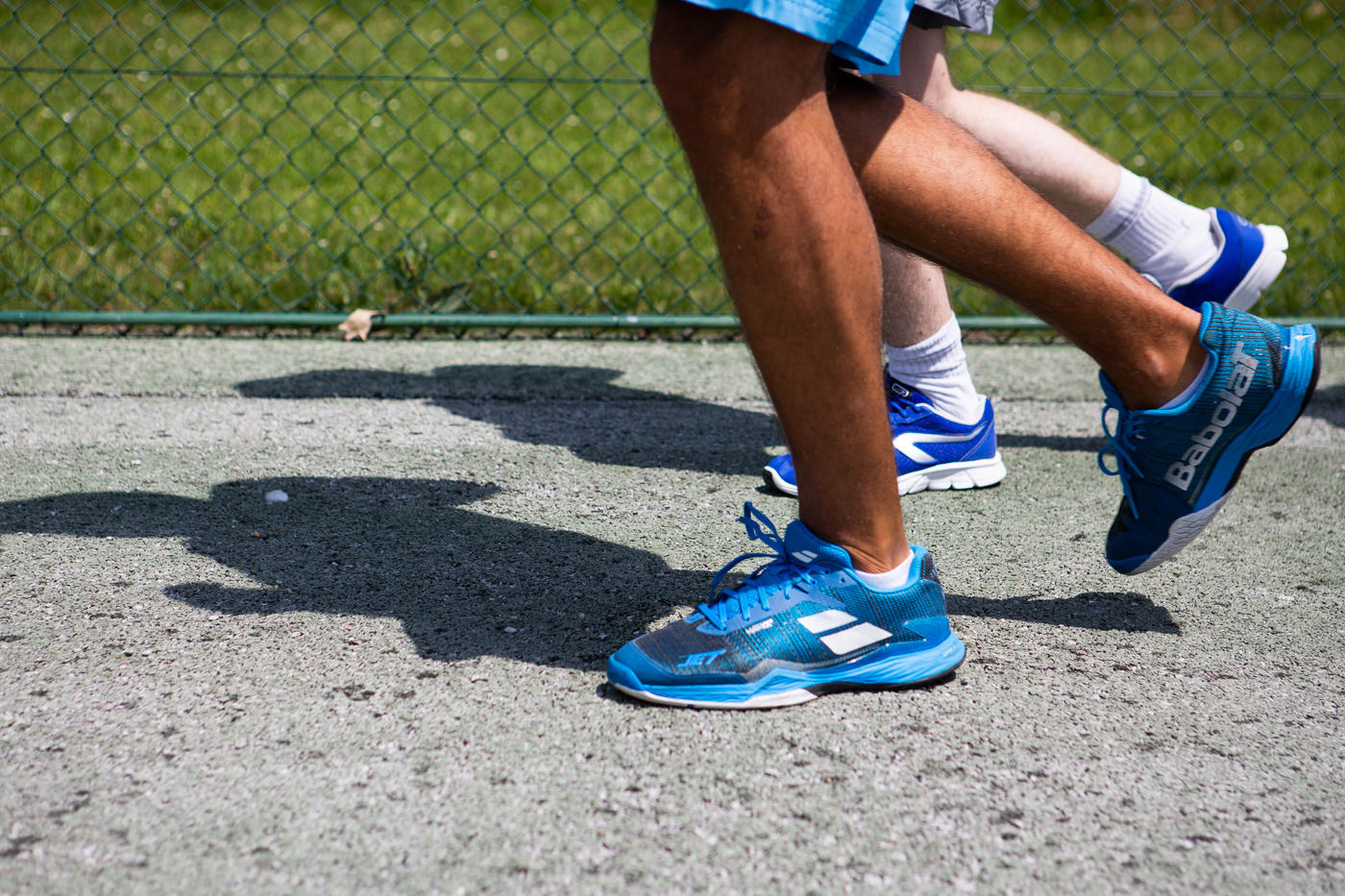 Deux hommes en train de courir pour s'échauffer sur le court de tennis.