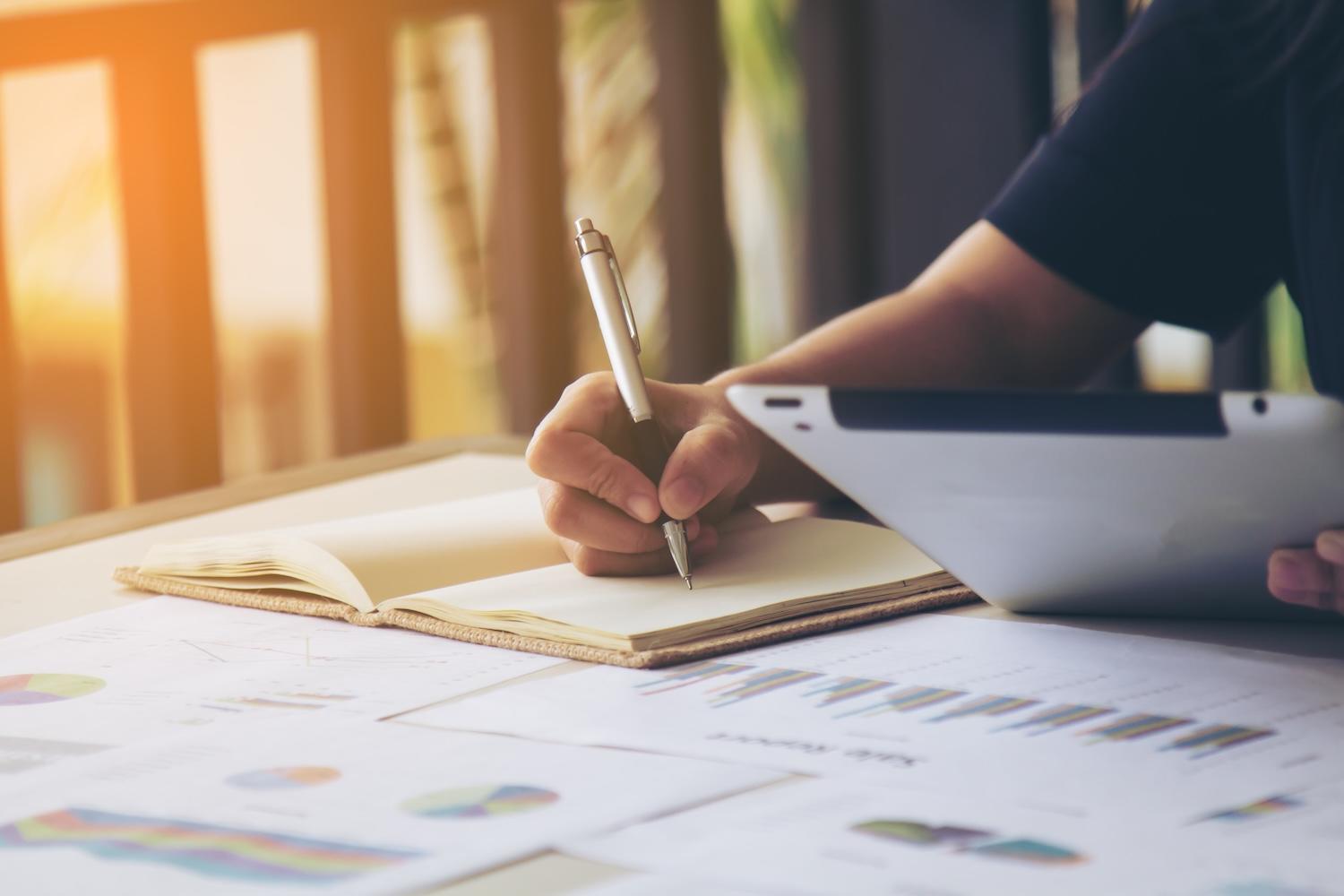 Une personne est en train d'écrire sur un cahier.