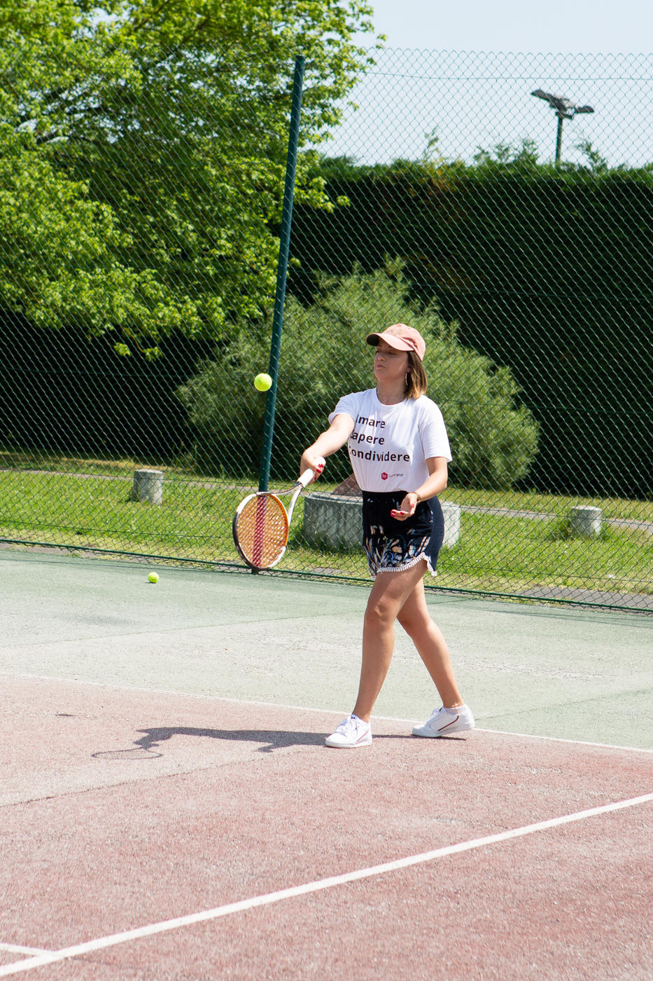 Jeune femme renvoyant une balle de tennis sur un court en dur en extérieur.