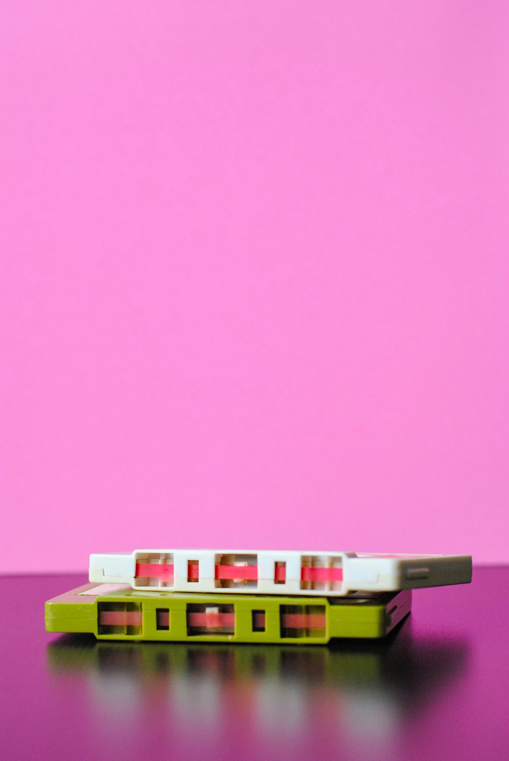 Deux cassettes audio sur fond rose.