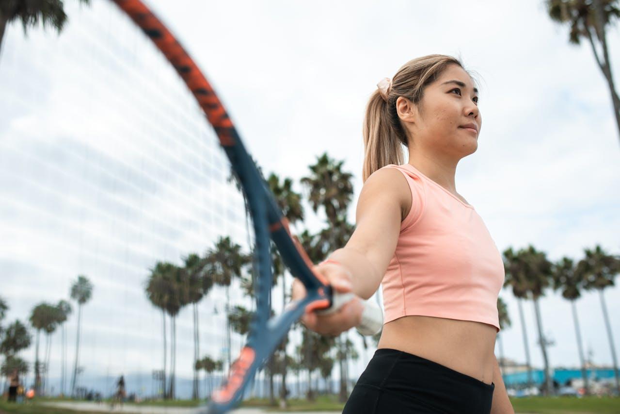 Jeune femme asiatique tenant une raquette de tennis dans la main.