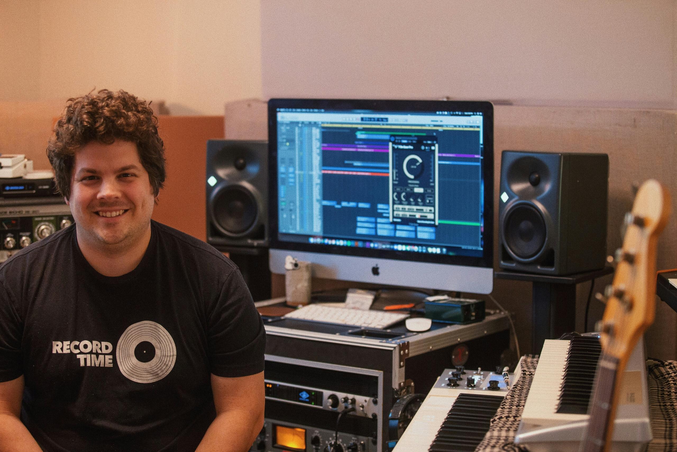 Un sound designer pose devant son bureau.