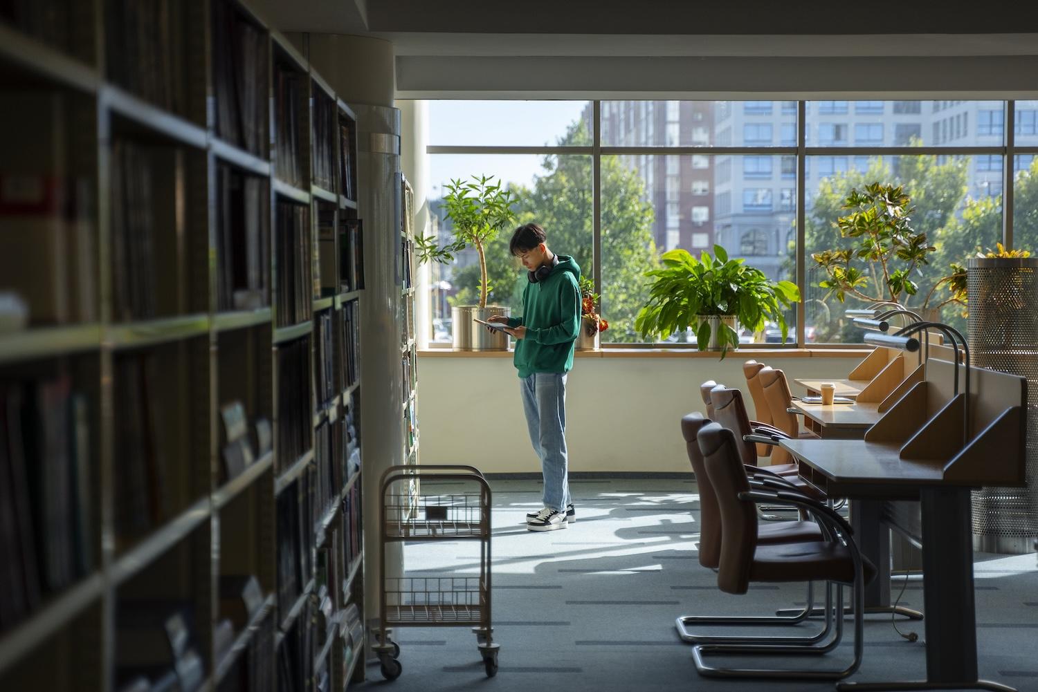 Un jeune étudiant est dans une bibliothèque universitaire.