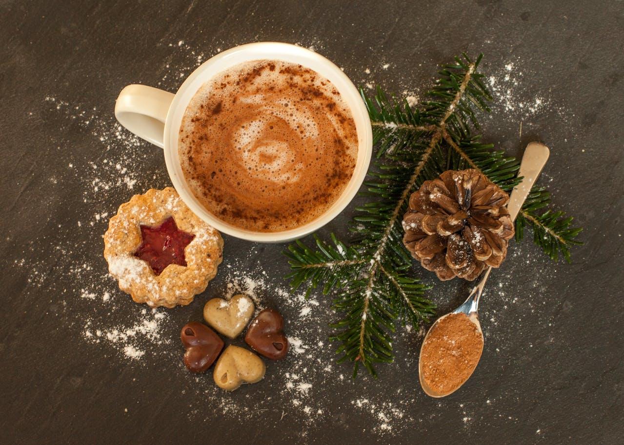Vue d'en haut d'un biscuit à la confiture posé à côté d'une tasse de chocolat chaud.