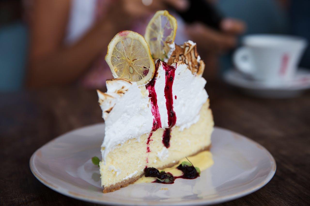 Un gros morceau de tarte au citron meringuée posée sur une assiette blanche