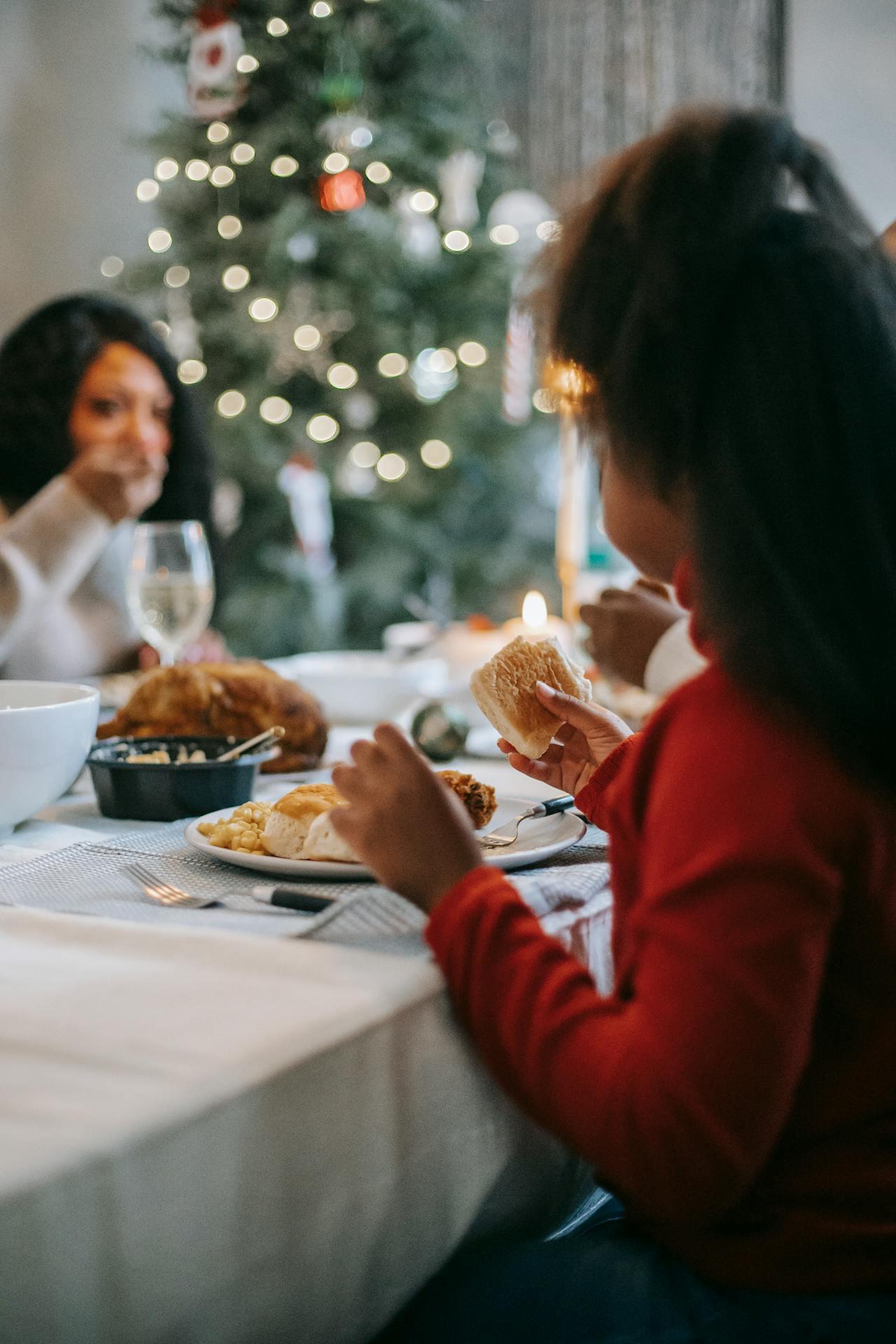 Jeune fille noire en train de manger ur une table de Noël. 