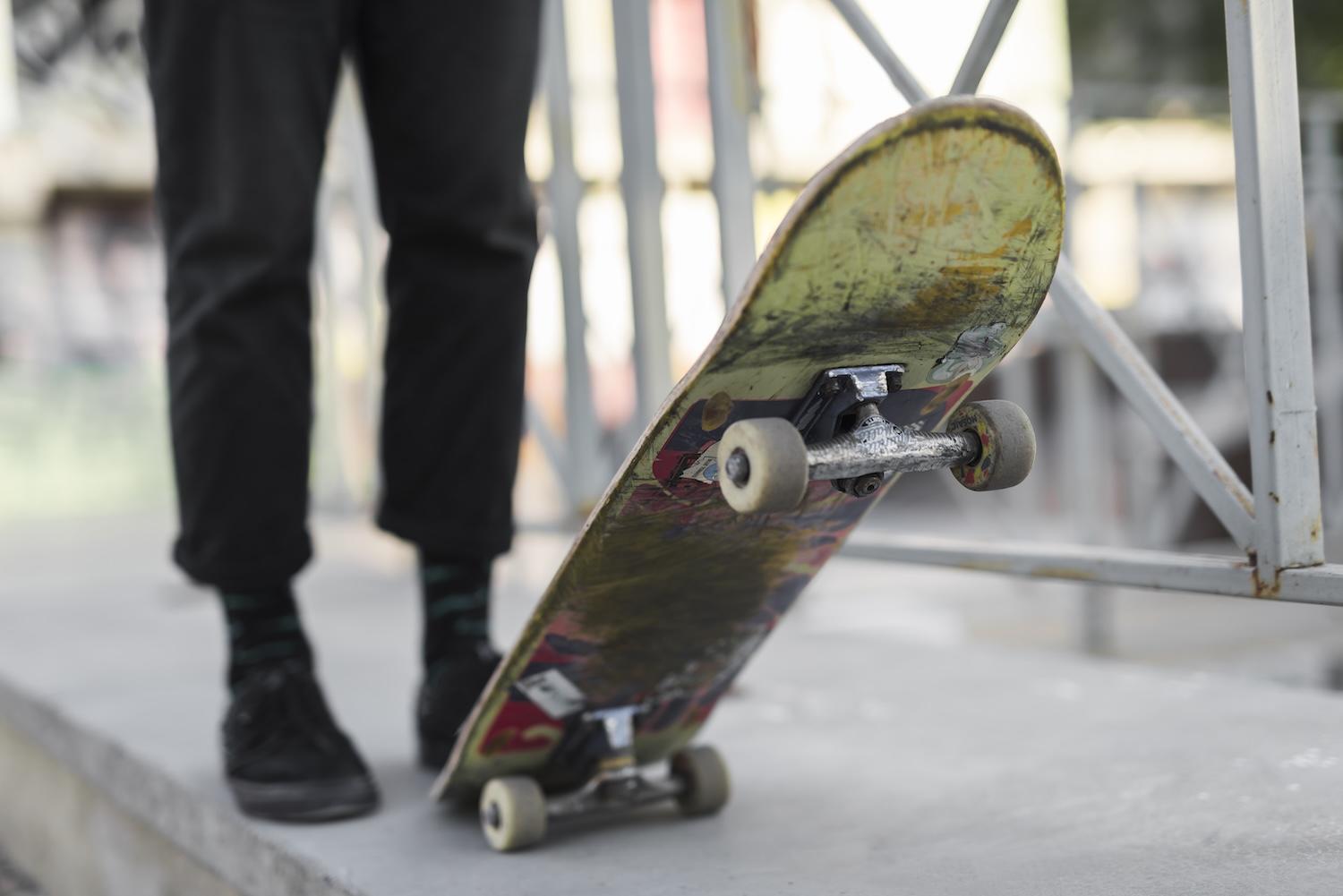 Une personne tient un skate avec son pied.