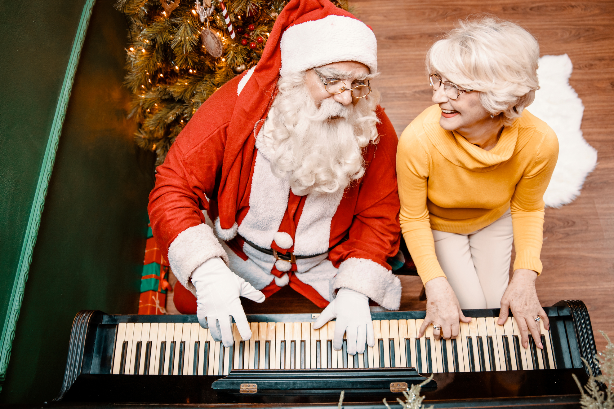 Un père Noël et une dame en train de jouer du piano ensemble.