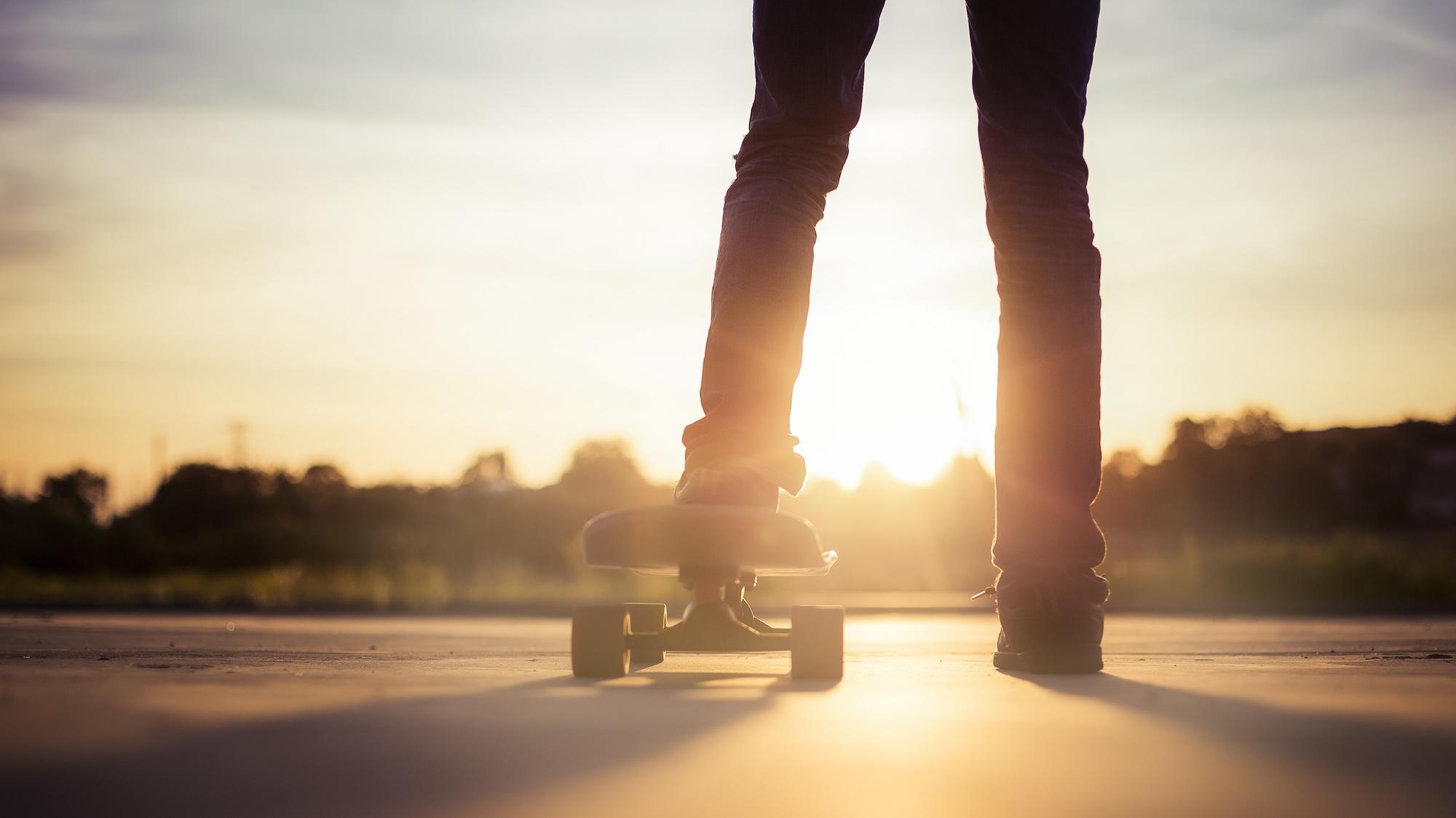 Gros plan sur les pieds d'un skateur au coucher du soleil