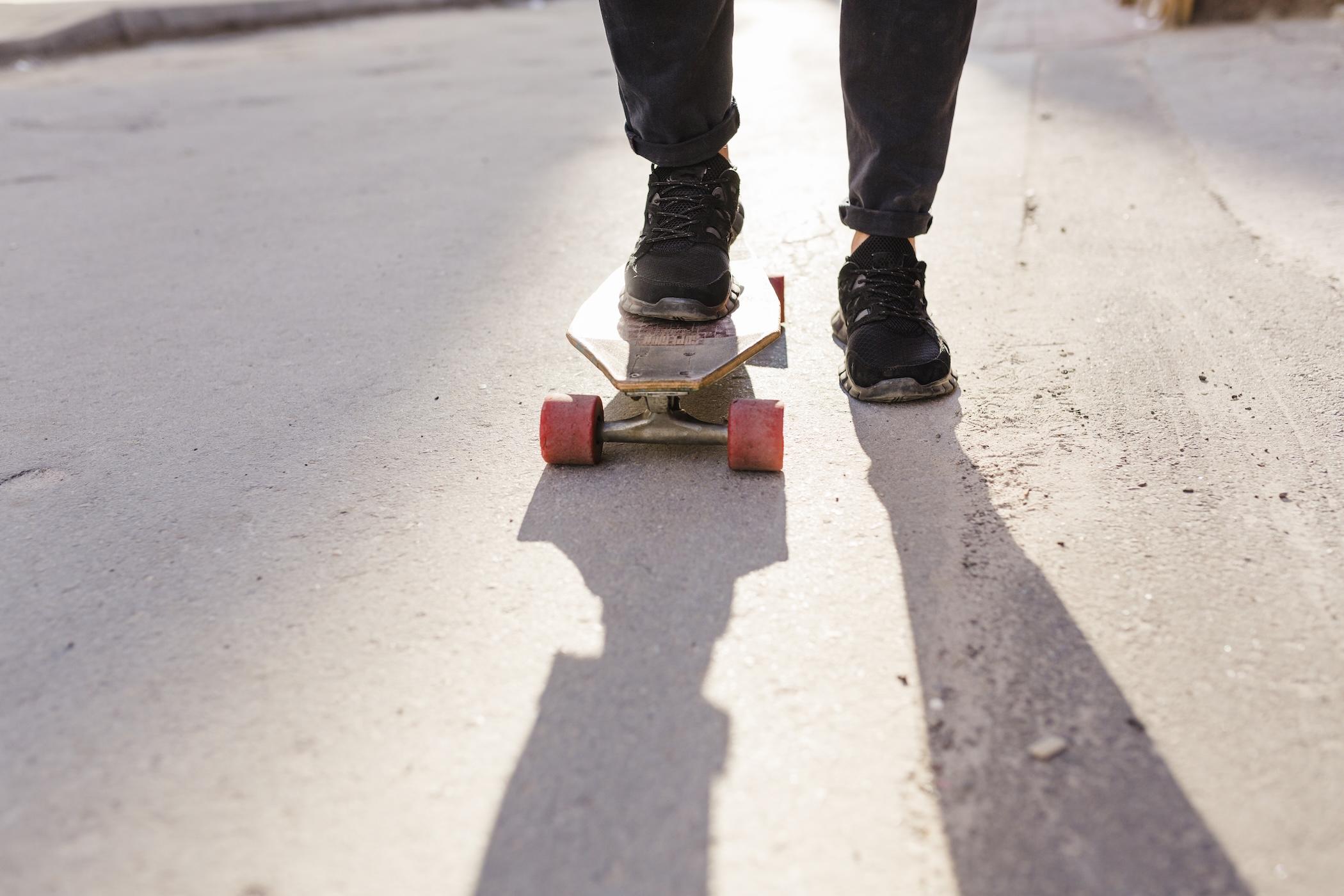 Vue des pieds d'un homme posés sur un skateboard.