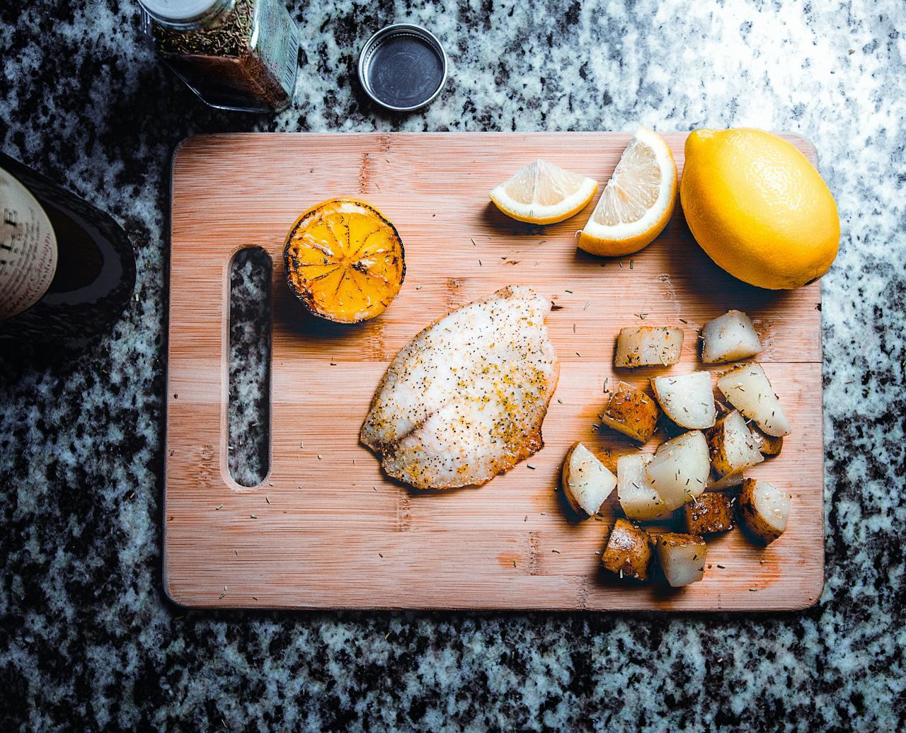 Poisson posé sur une planche à découper avec du citron.