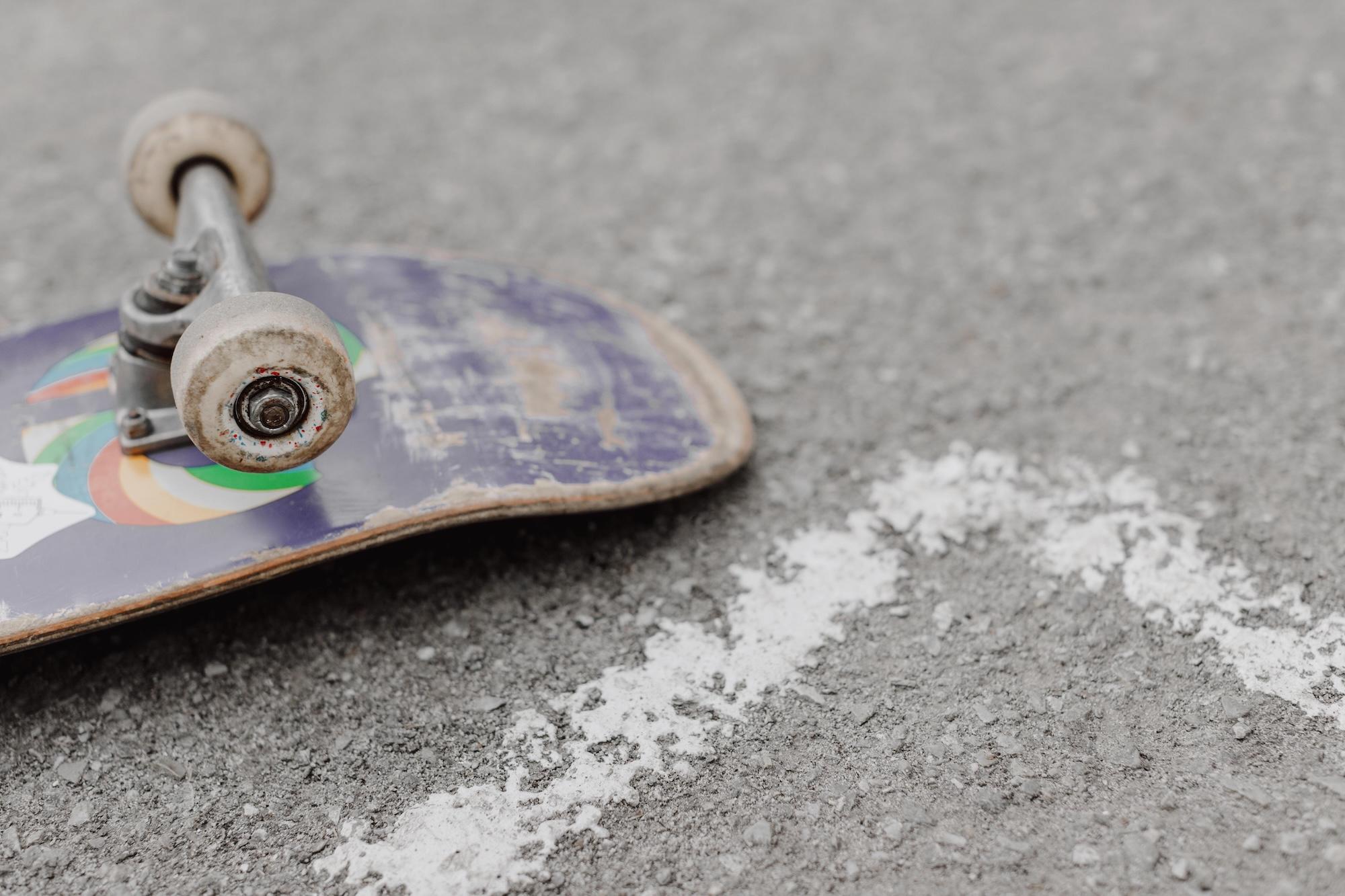Une planche de skate est posée à l'envers sur le bitume.