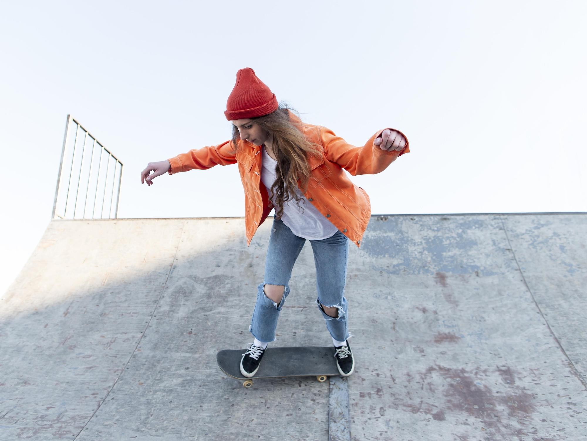 Une jeune femme est en train de faire du skate.