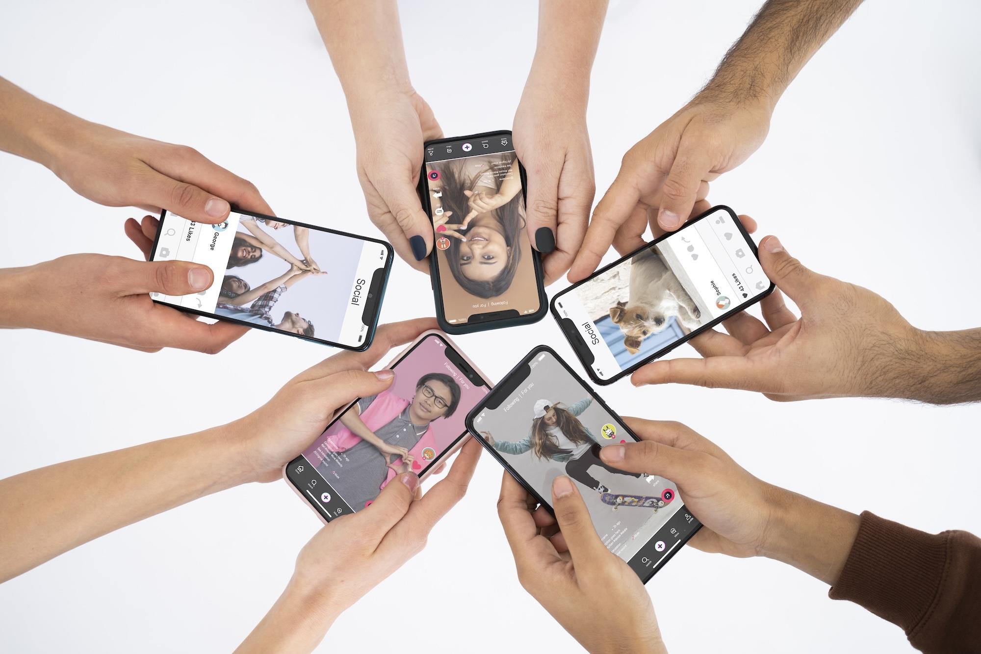 Plusieurs mains en étoile tiennent des smartphones