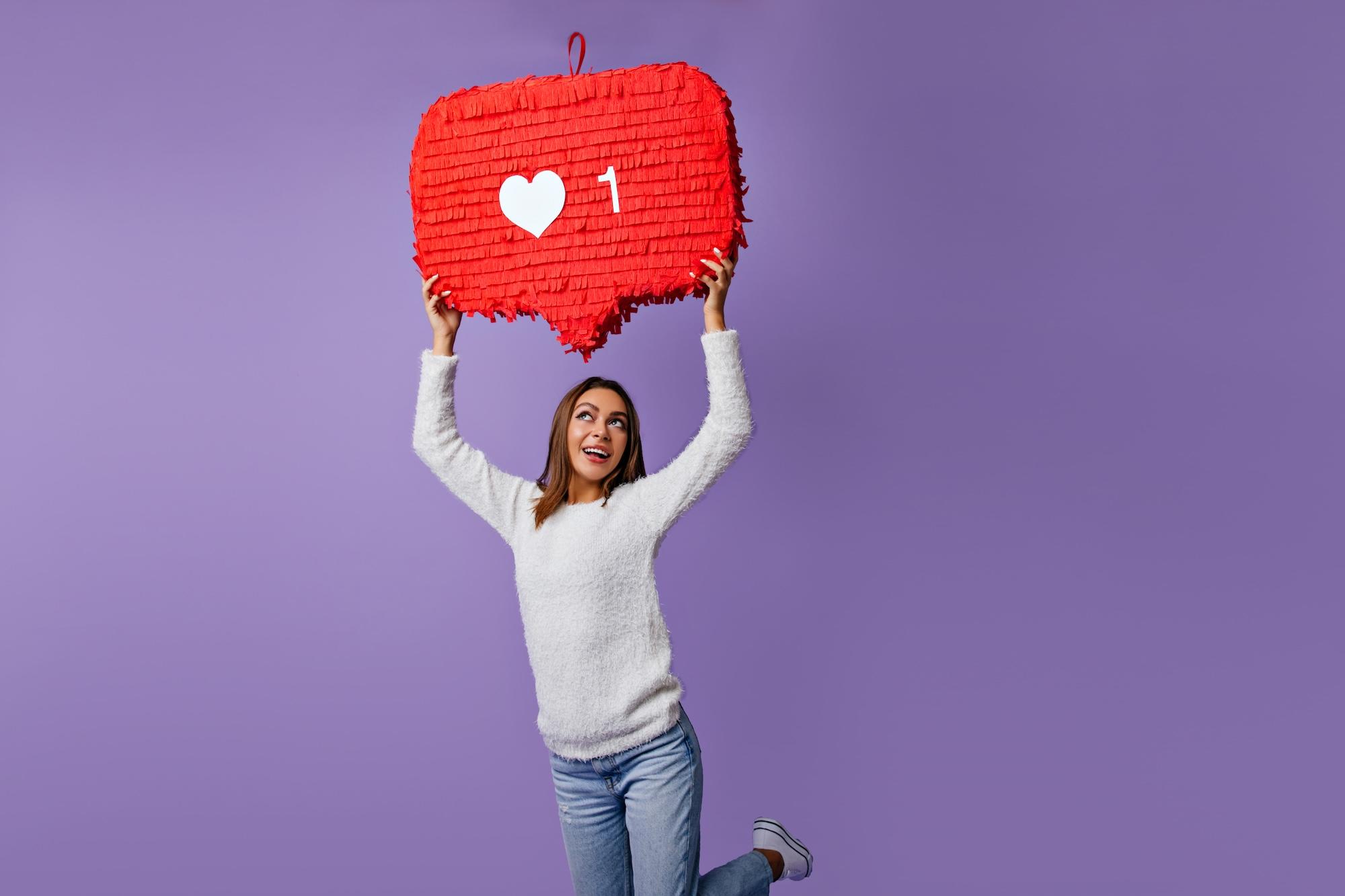 Une jeune femme tient un like rouge dans ses mains