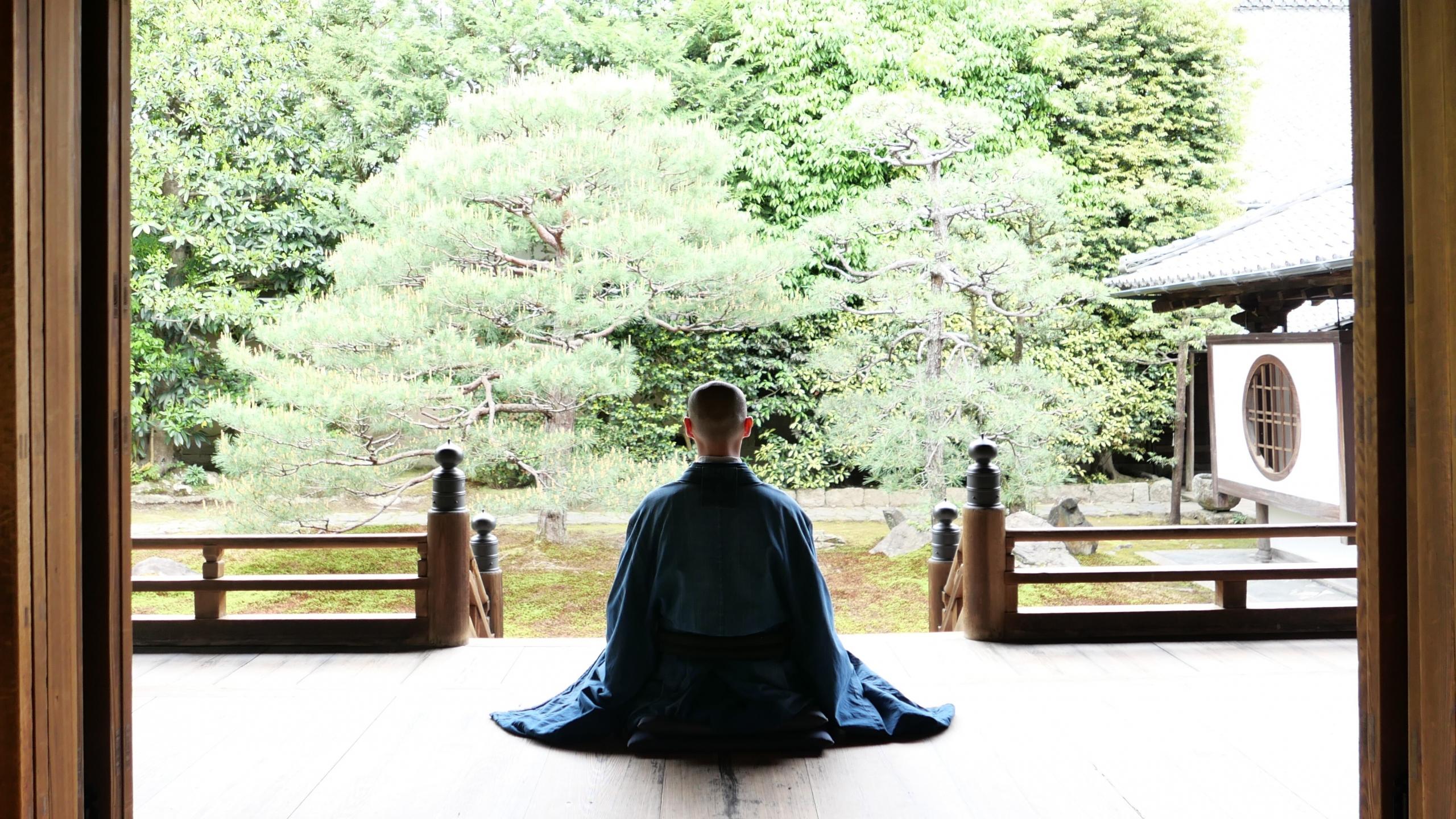 moine bouddhiste en position zen à l'entrée de son temple