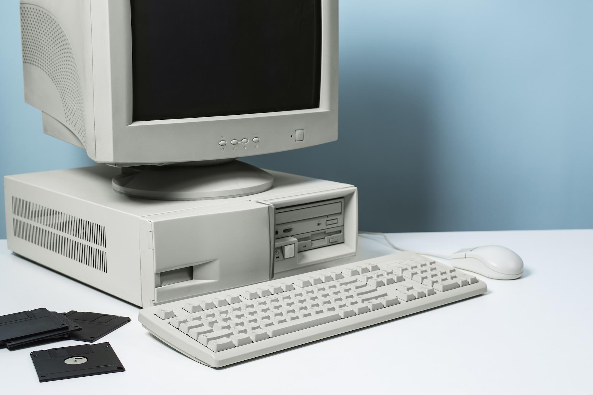 Un vieil ordinateur avec un clavier et des disquettes à sa gauche