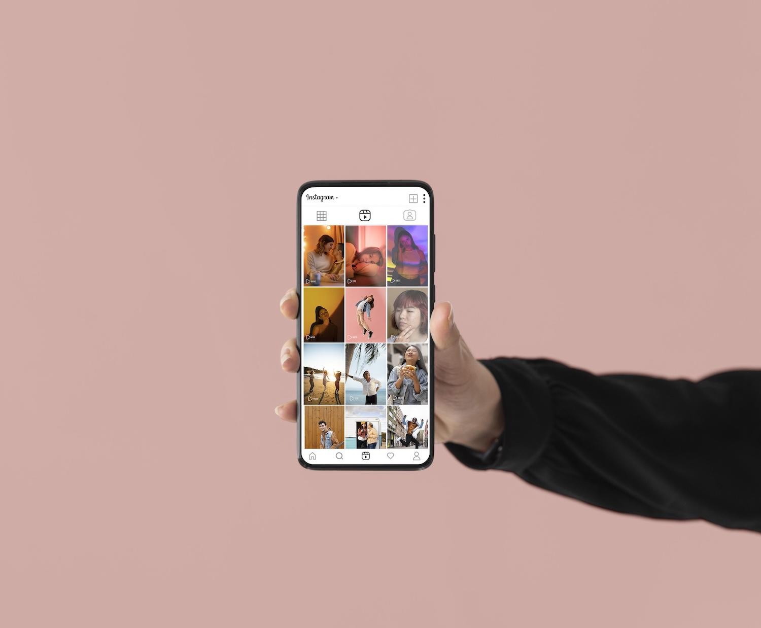 Une main tient un smartphone avec l'application Instagram ouverte.