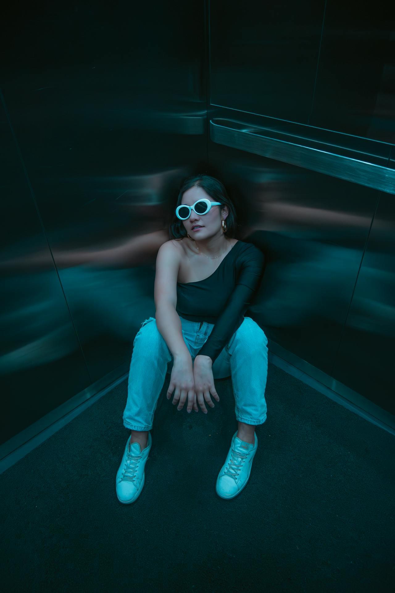 Jeune femme assise dans un ascenseur.