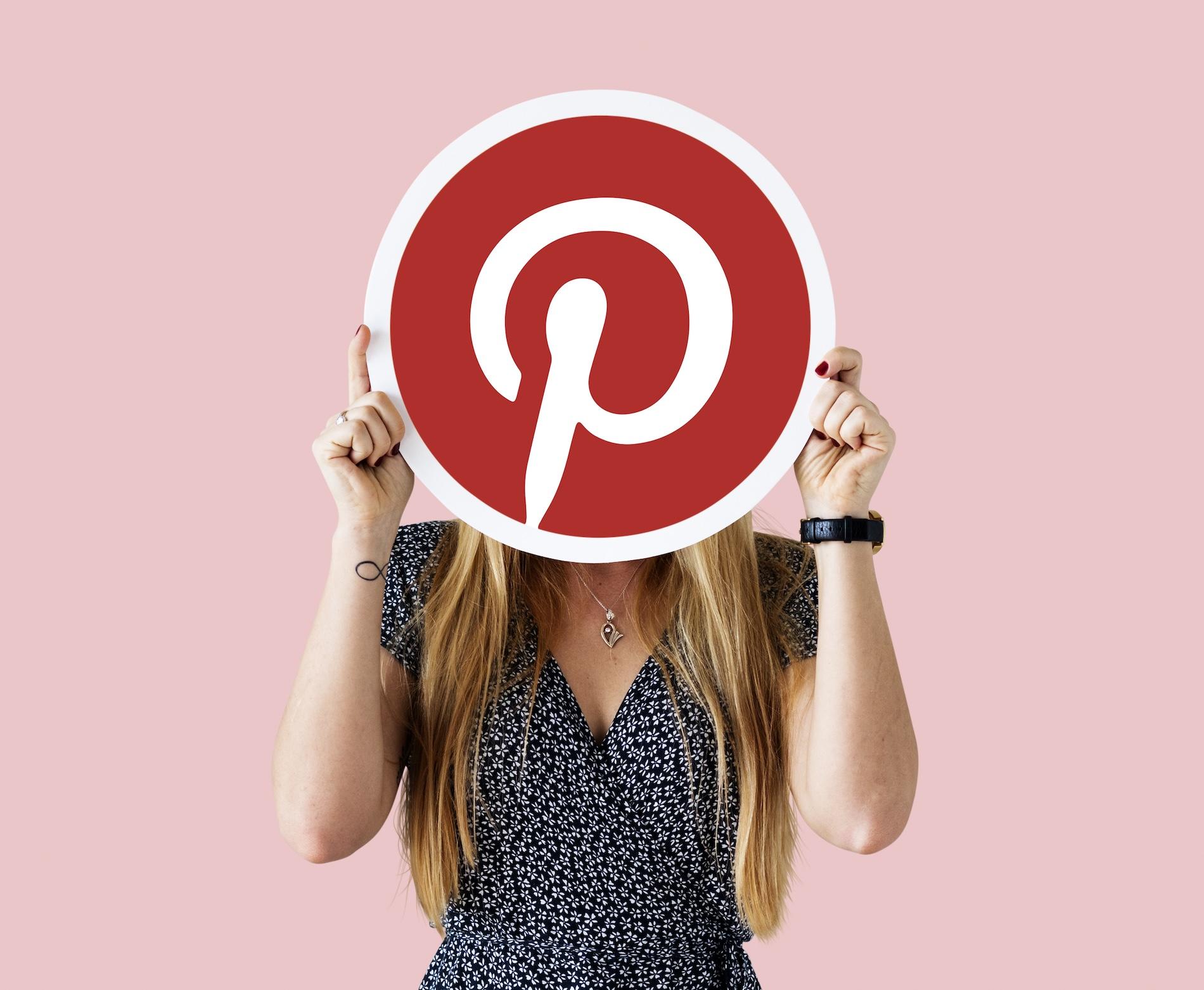 Une jeune femme tient le logo Pinterest dans ses mains.