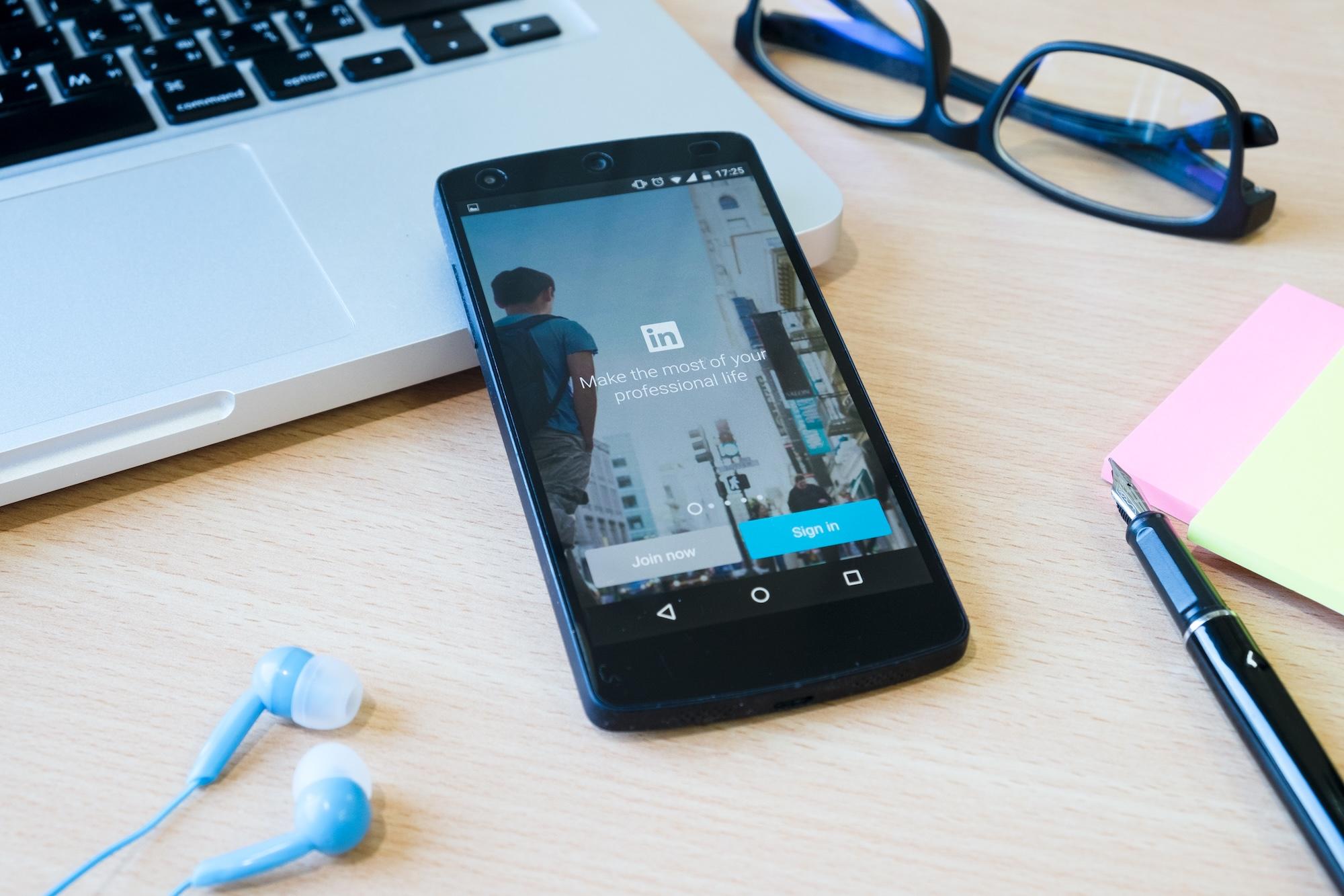 Affichage de l'appli LinkedIn sur un smartphone posé sur un bureau.