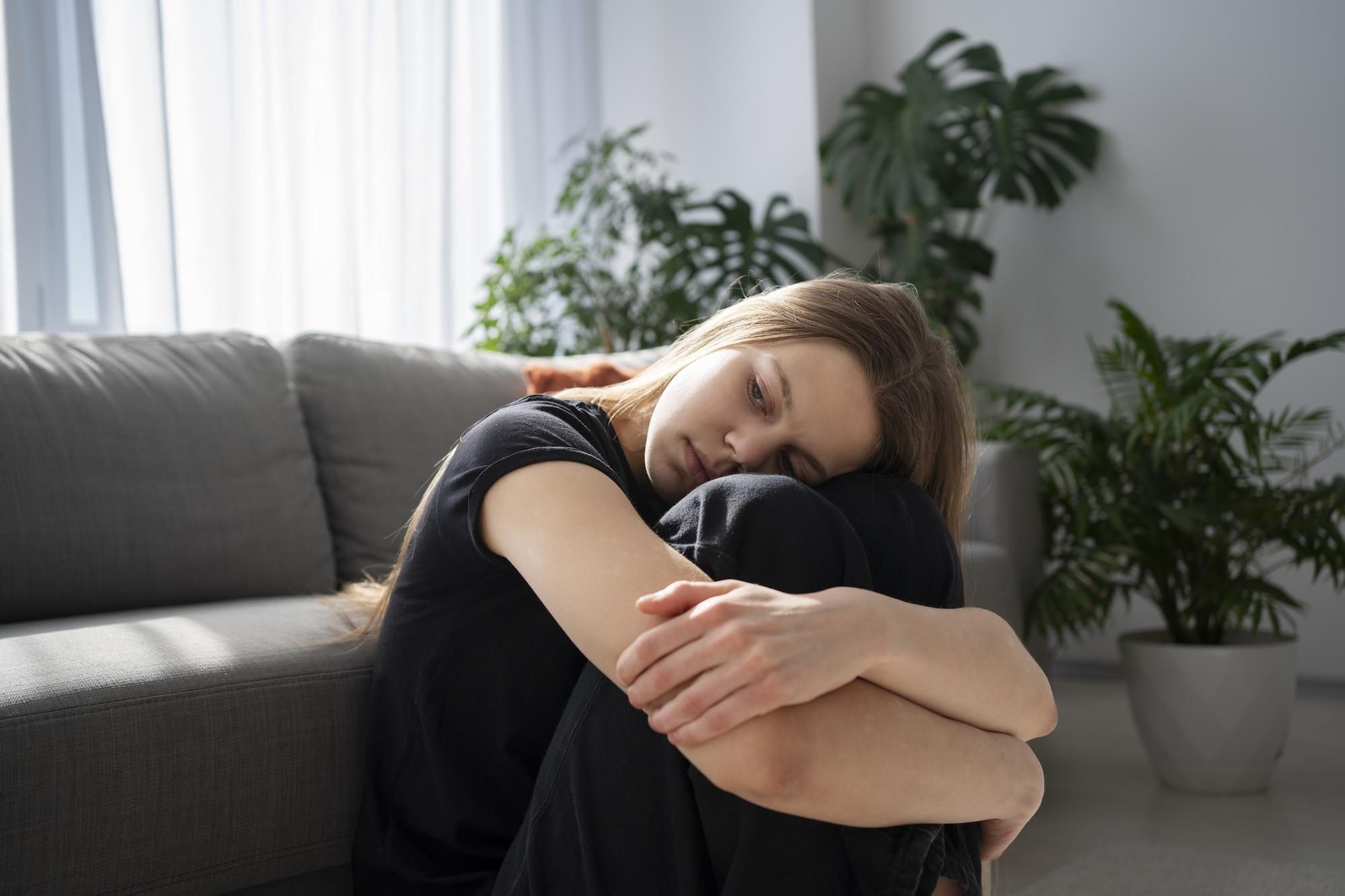 Jeune femme triste à la maison devant un canapé