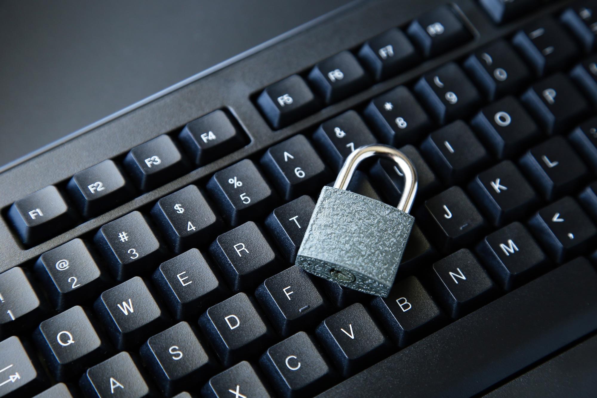 Un verrou sur un clavier d'ordinateur noir sur une surface noire.