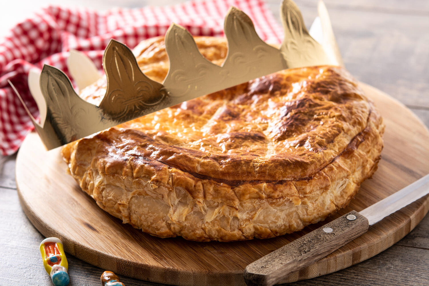 Galette des rois posée sur une planche en bois avec une couronne dorée dessus.