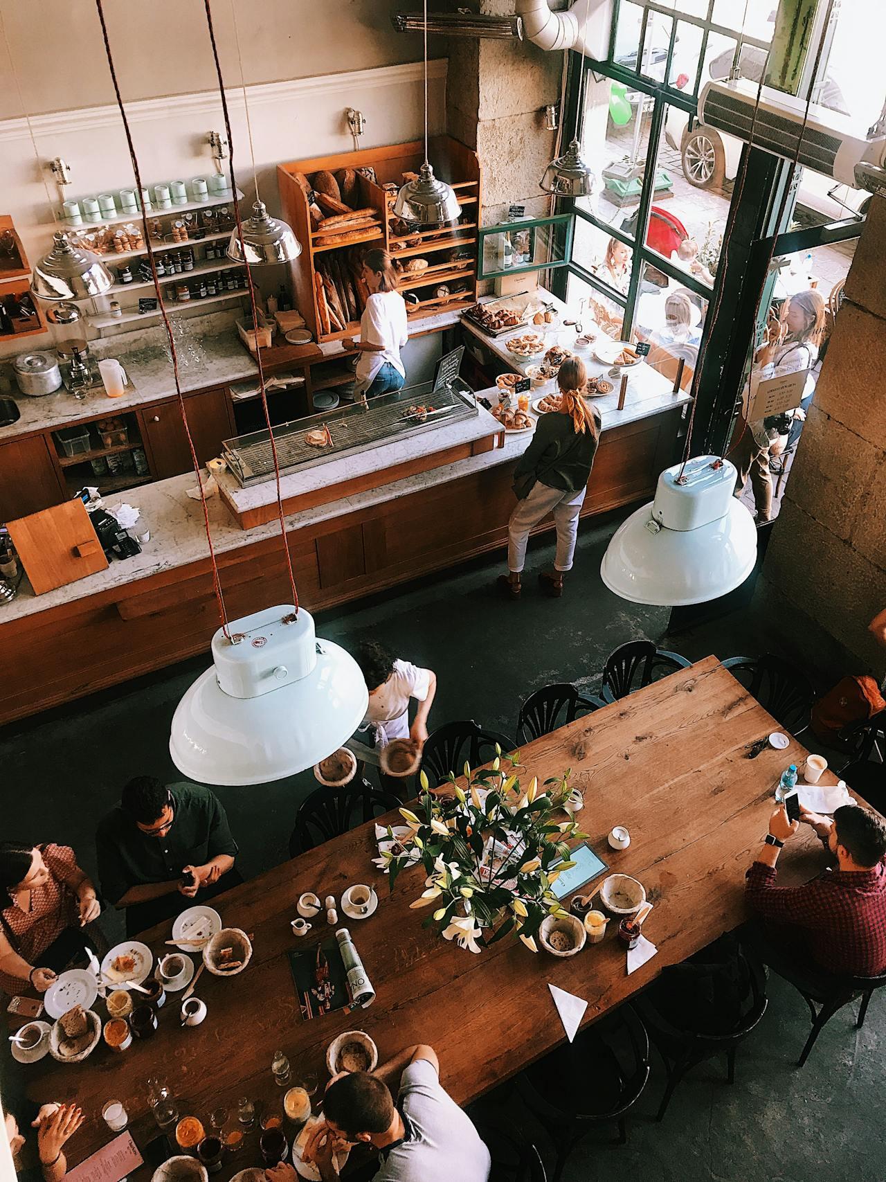 Vue d'en haut et de l'intérieur d'une boulangerie-pâtisserie avec une table centrale pour déguster les douceurs. 