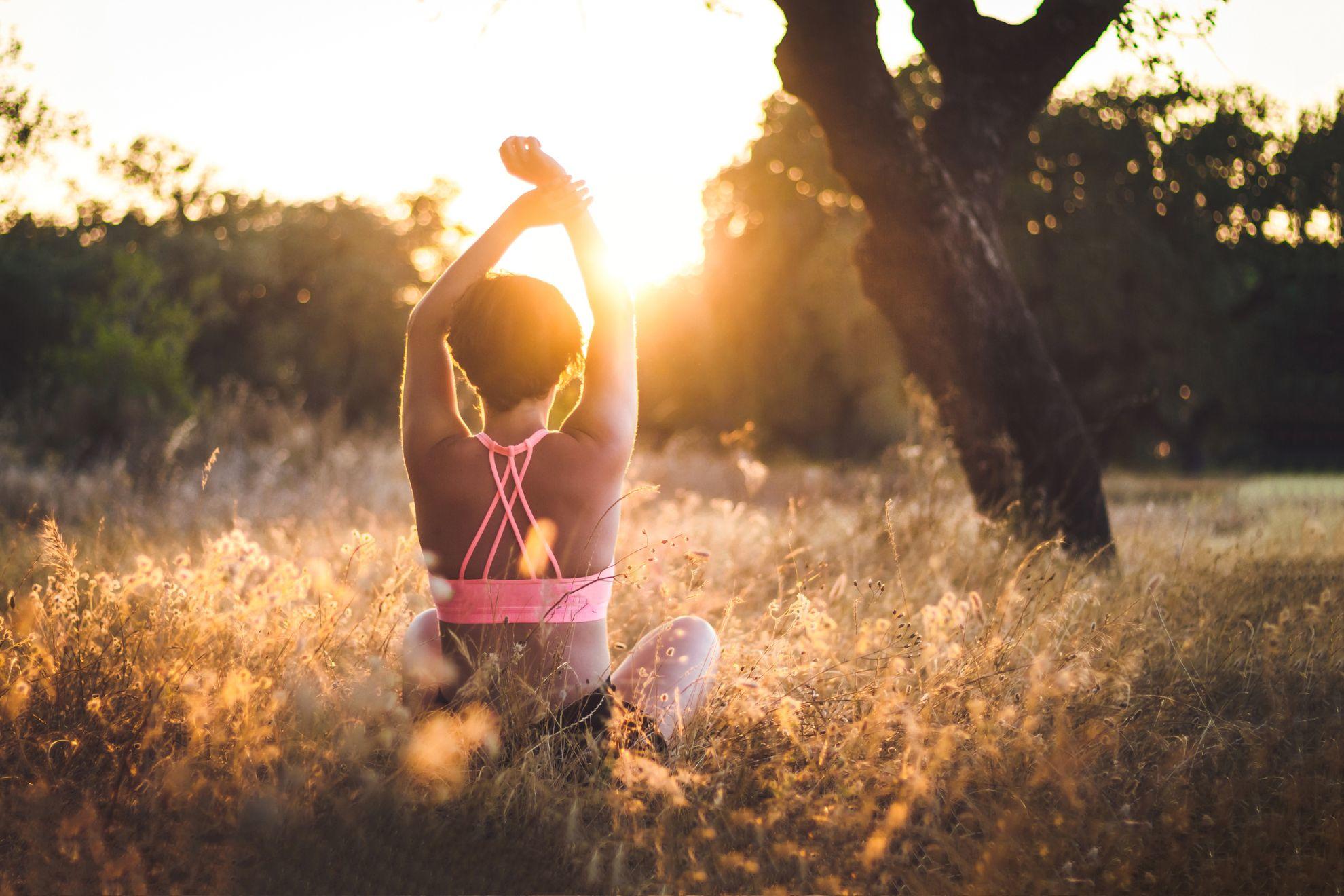 Une femme en train de faire sa séance de yoga en pleine nature.