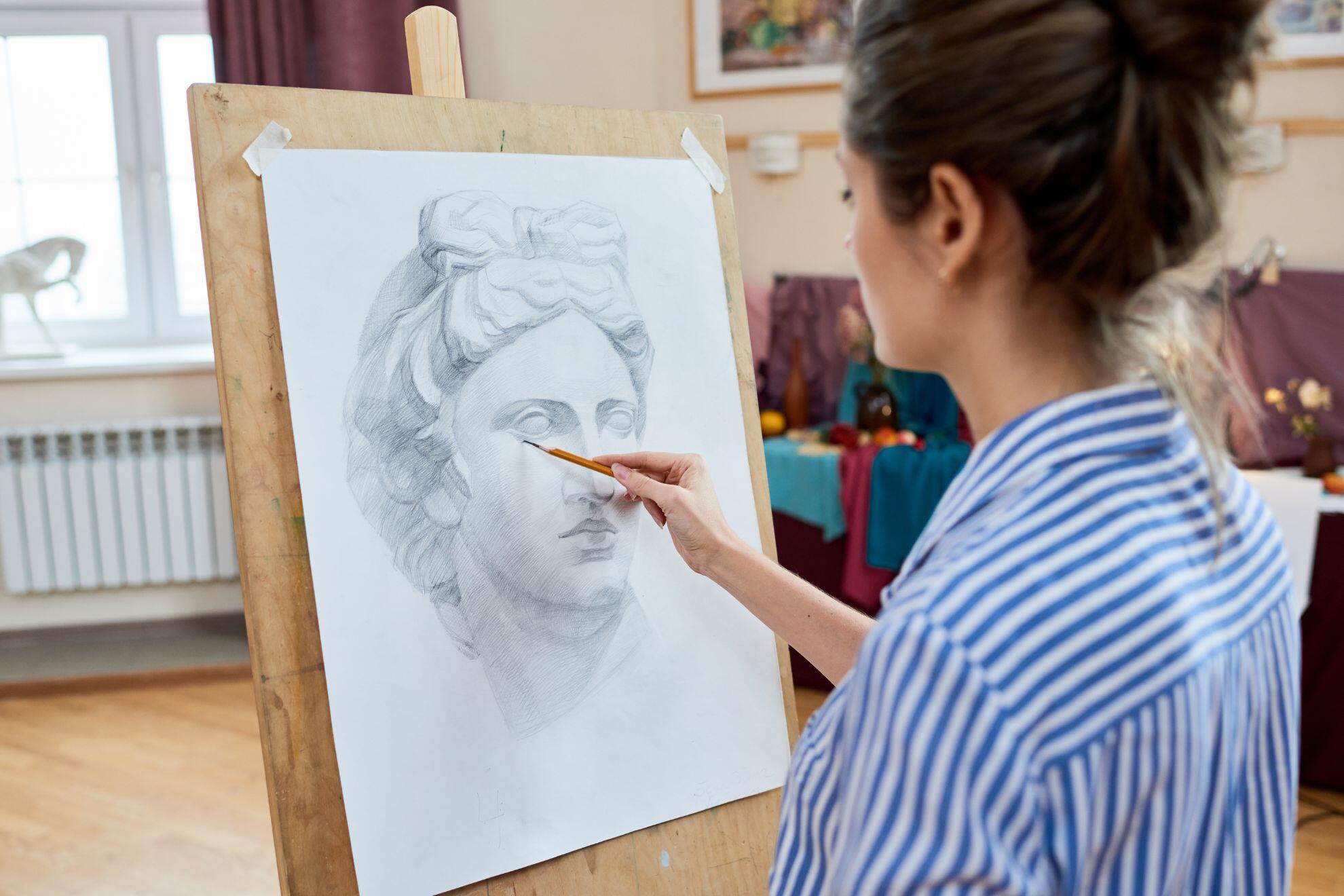 Une femme en train de dessiner une statue grecque.