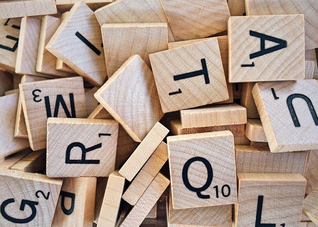 Lettres écrites en noir sur des carrés en bois clair.