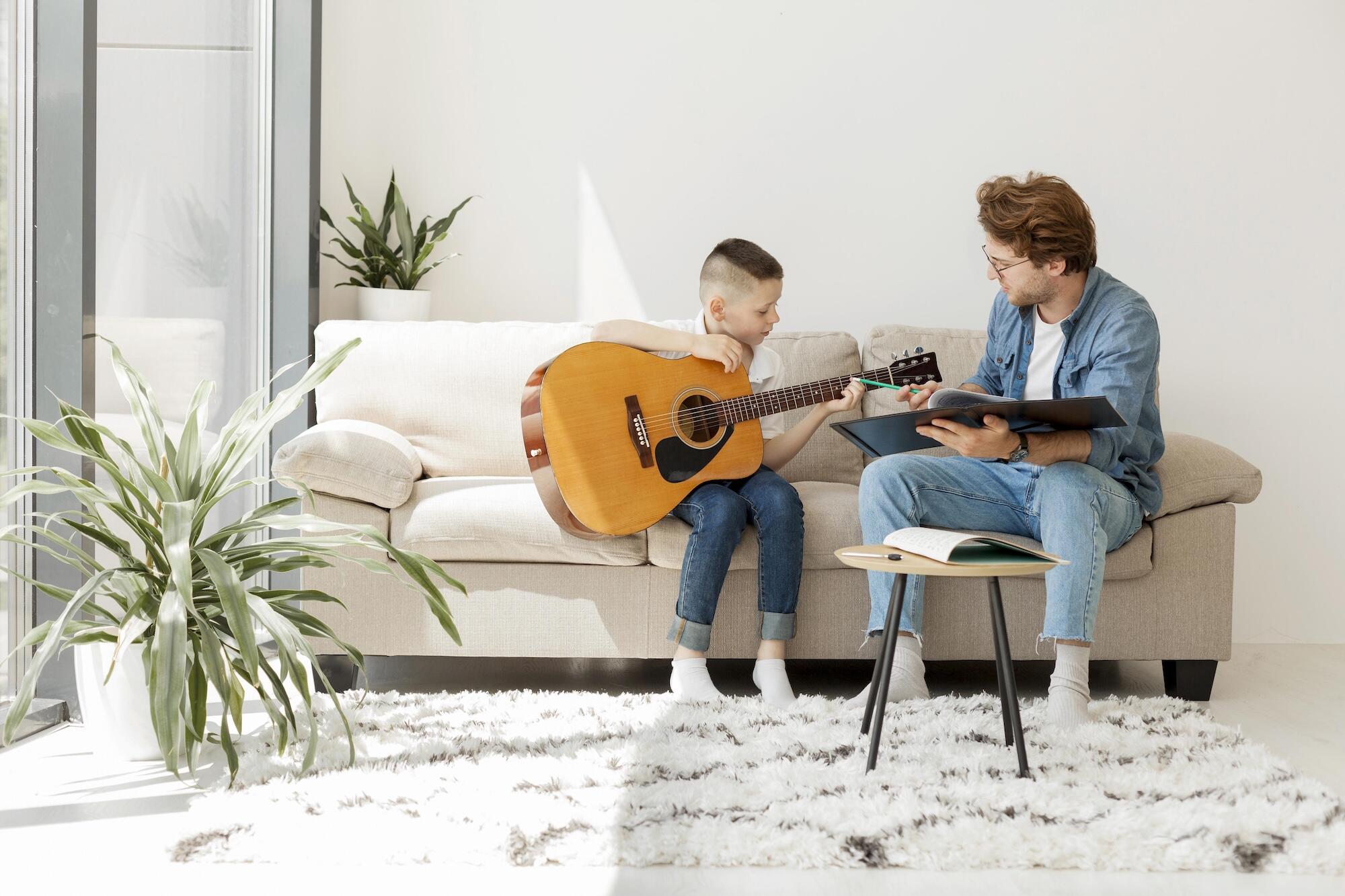 Un professeur enseigne la guitare à un enfant sur un canapé