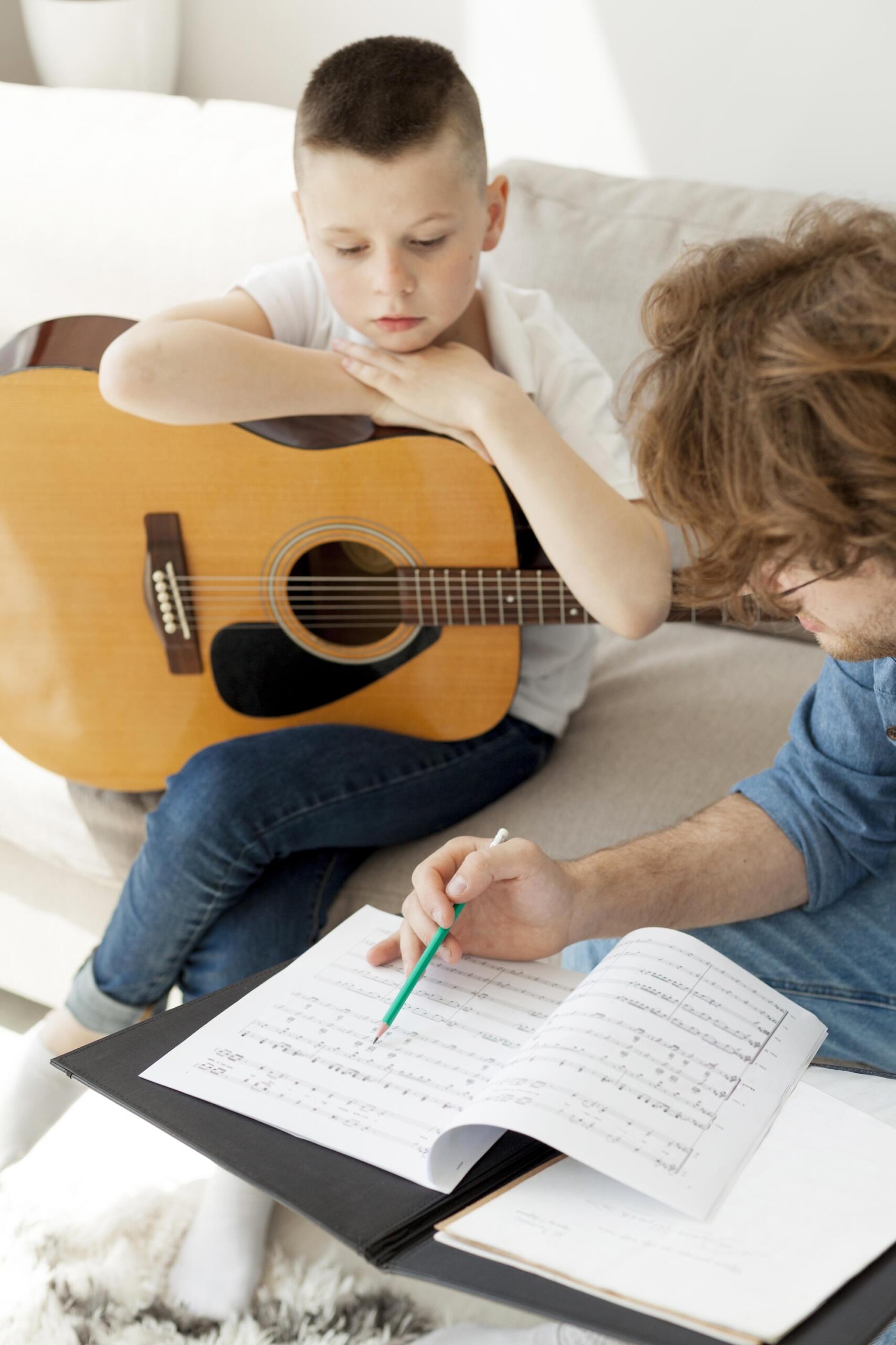 Un prof donne un cours de guitare particulier à un enfant