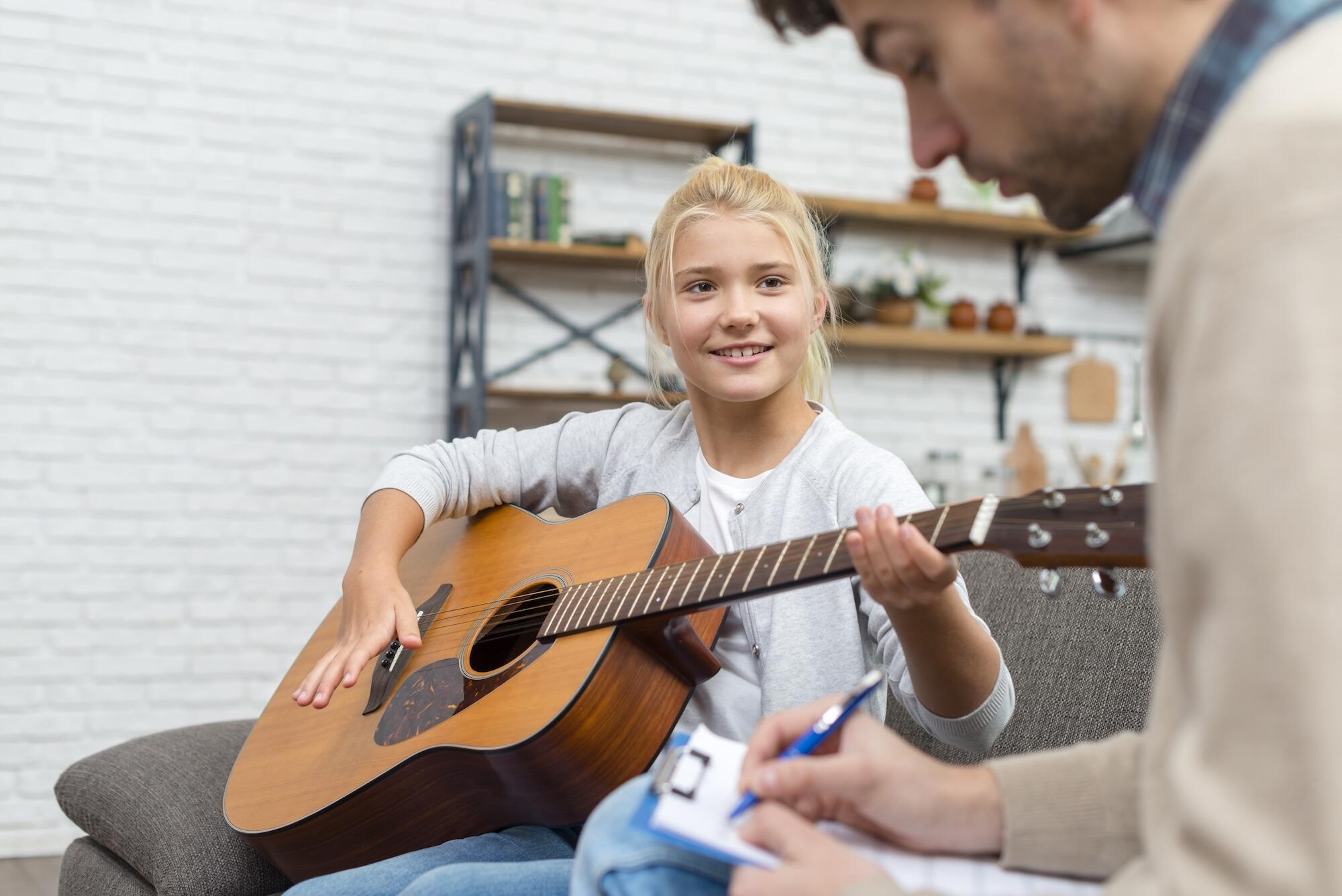 Une jeune fille est en train d'apprendre à jouer de la guitare