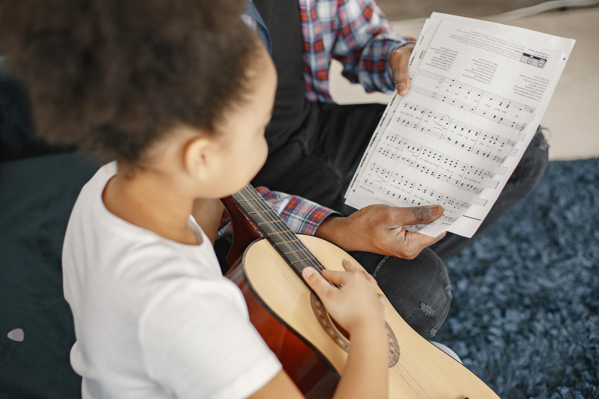 Une petit fille est en train d'apprendre la guitare