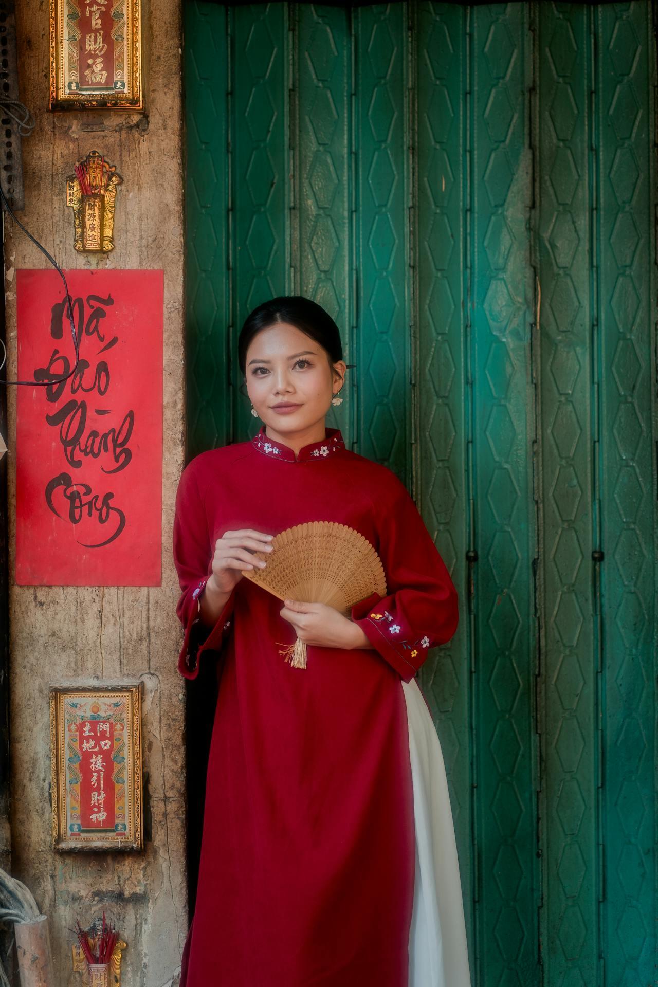 Jeune vietnamienne en tenue traditionnelle devant un panneau écrit en vietnamien.