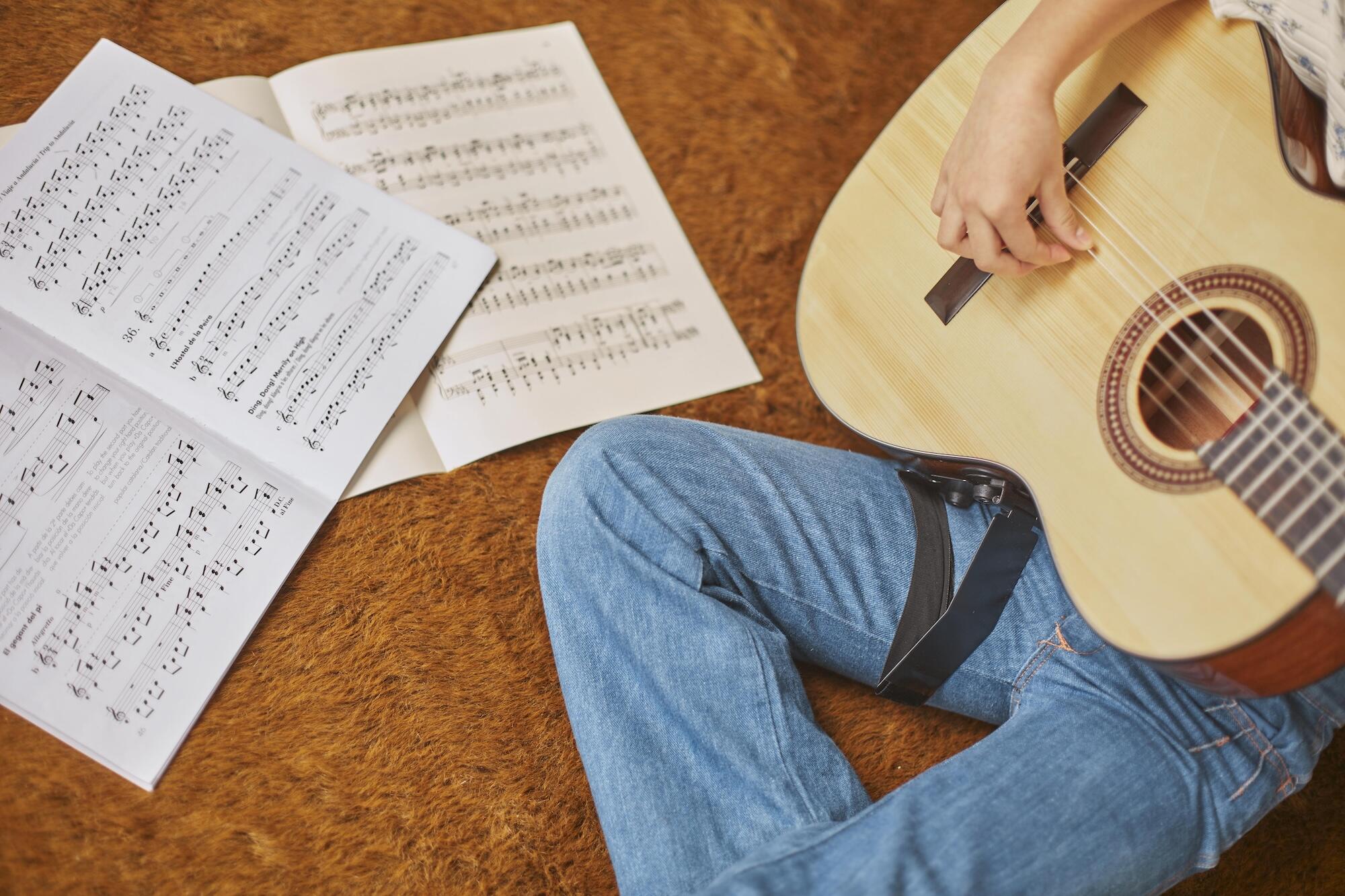 Une fille apprend à jouer de la guitare à la maison