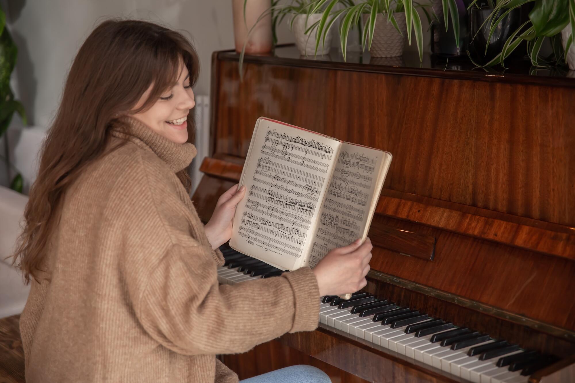 Une musicienne enseigne un morceau assise devant les notes du piano.