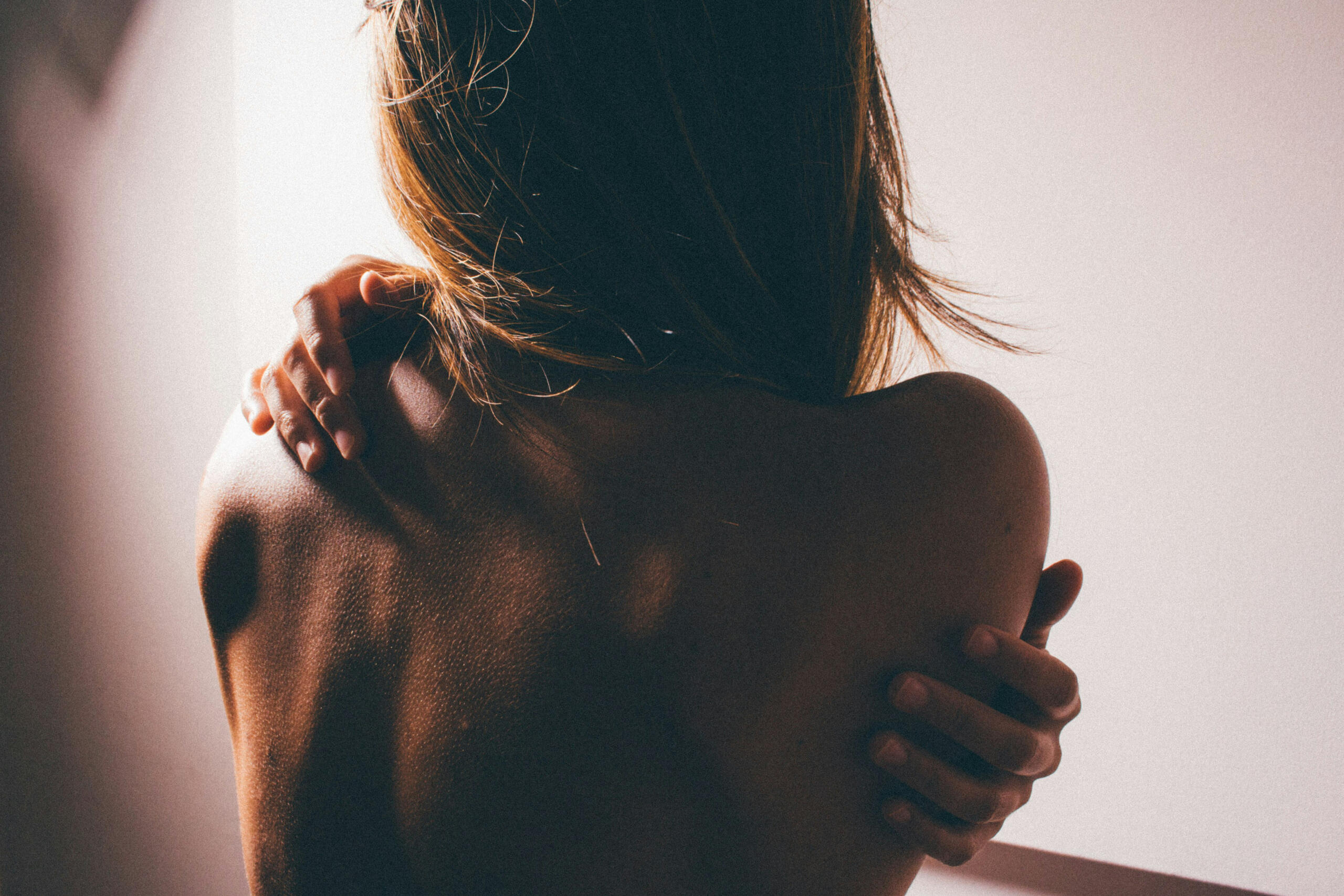 Une femme se tient le dos par les deux mains.