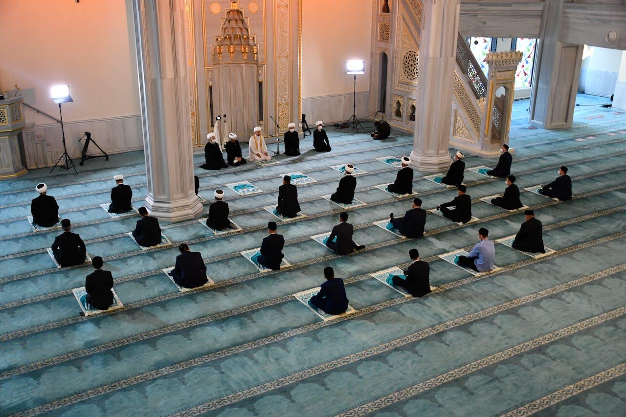 homme musulmans a genoux sur leur tapis de priere dans une mosquee