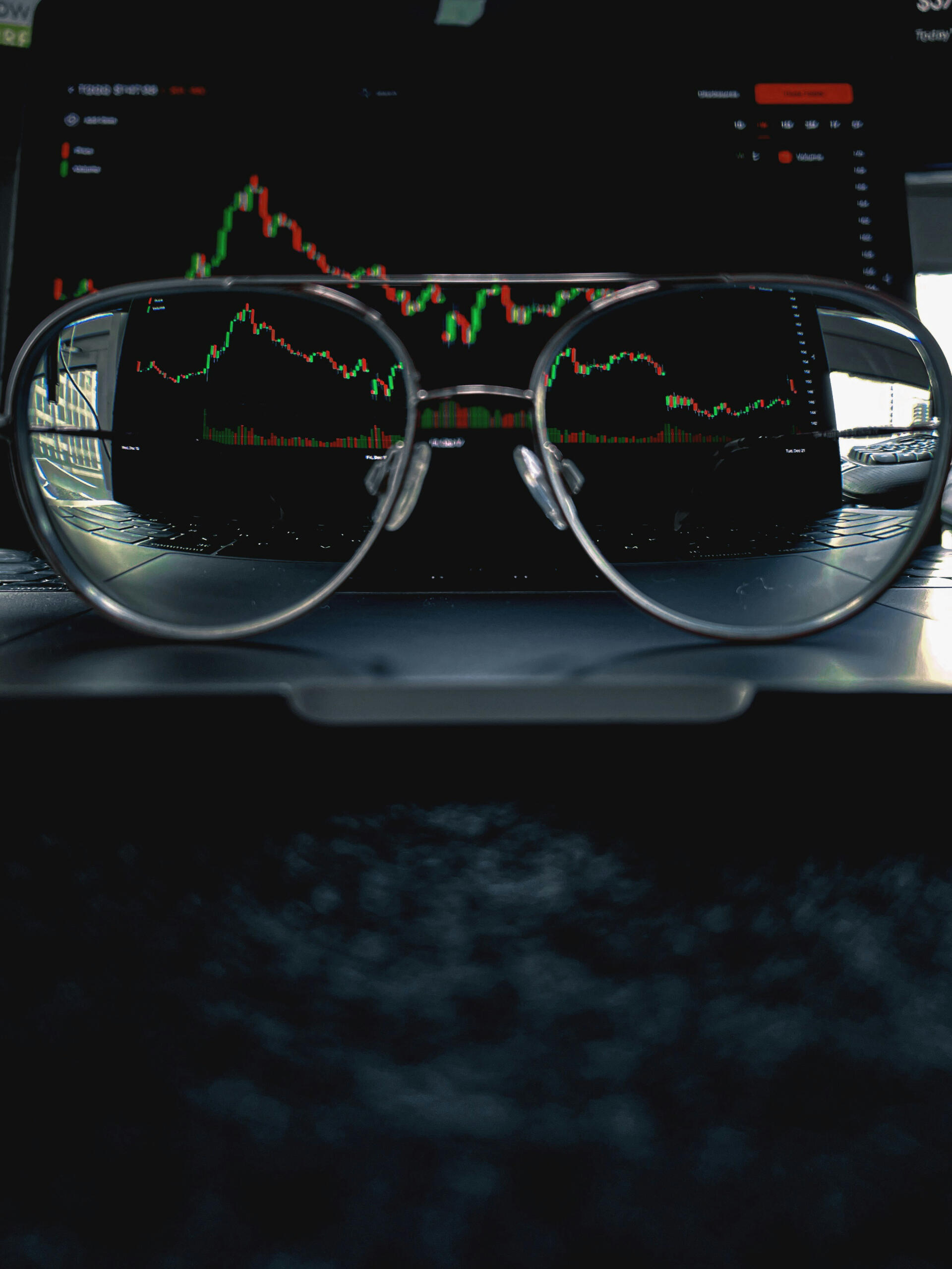Une paire de lunettes posée devant un graphique financier.