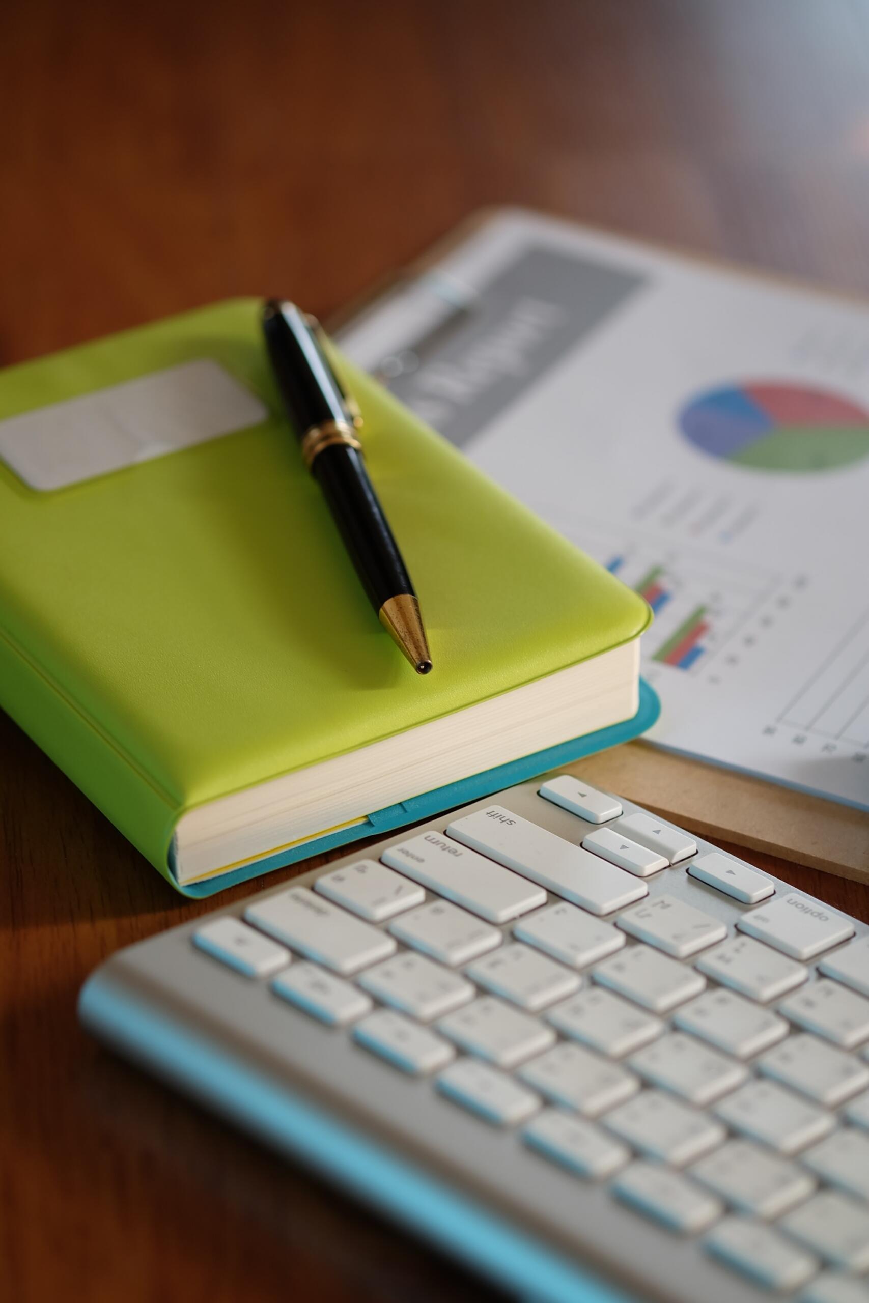Un carnet de note est posé sur le bureau à côté du clavier.